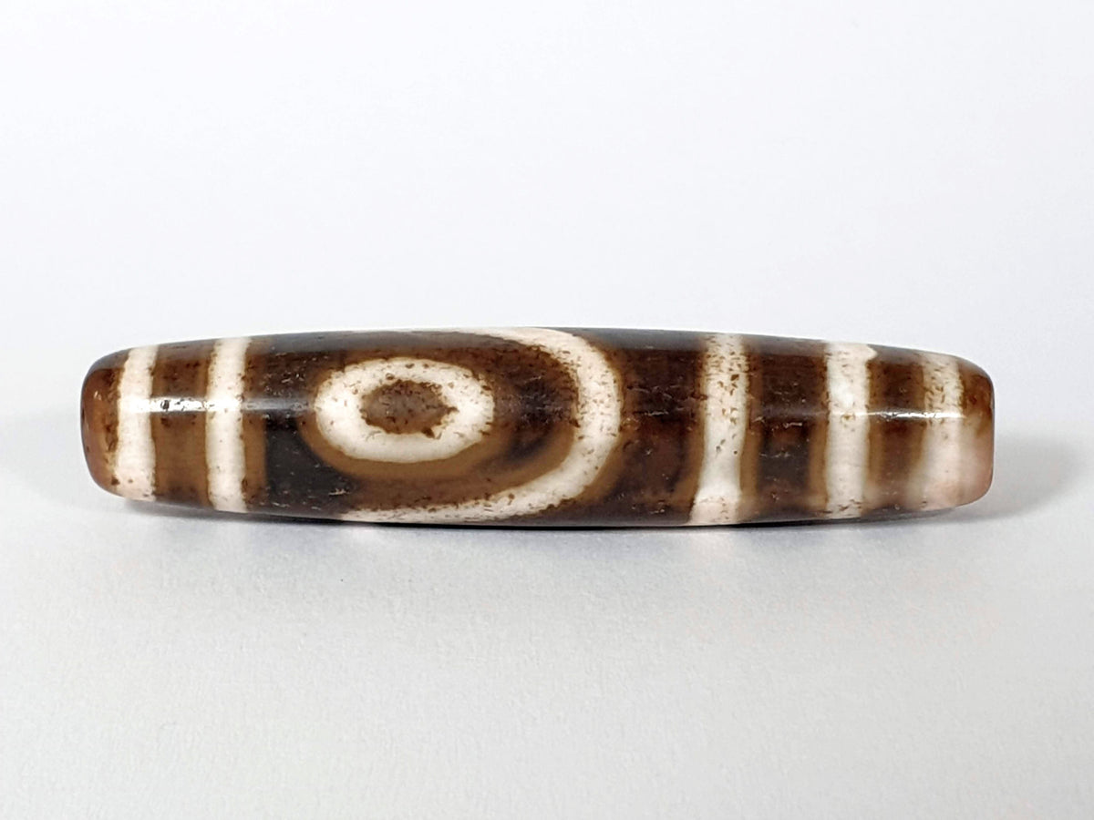 Qing Dynasty two eye dzi — third face, second spiral eye on warm brown ground with pink-blush end, bracket bars, At-0426-2EQ