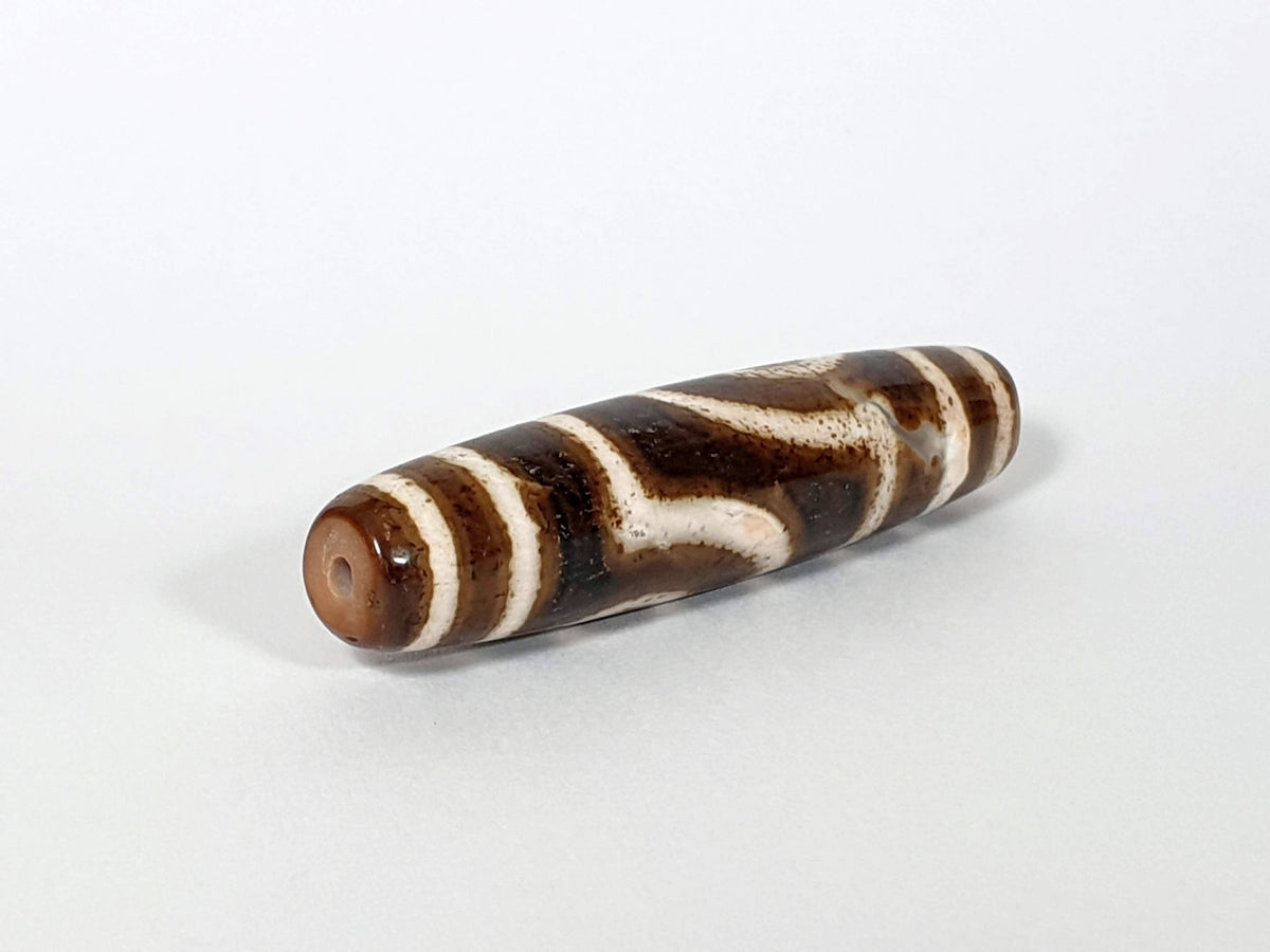 Qing Dynasty two eye dzi — angled end, drill hole at warm brown rounded right tip, wave pattern on body, At-0426-2EQ