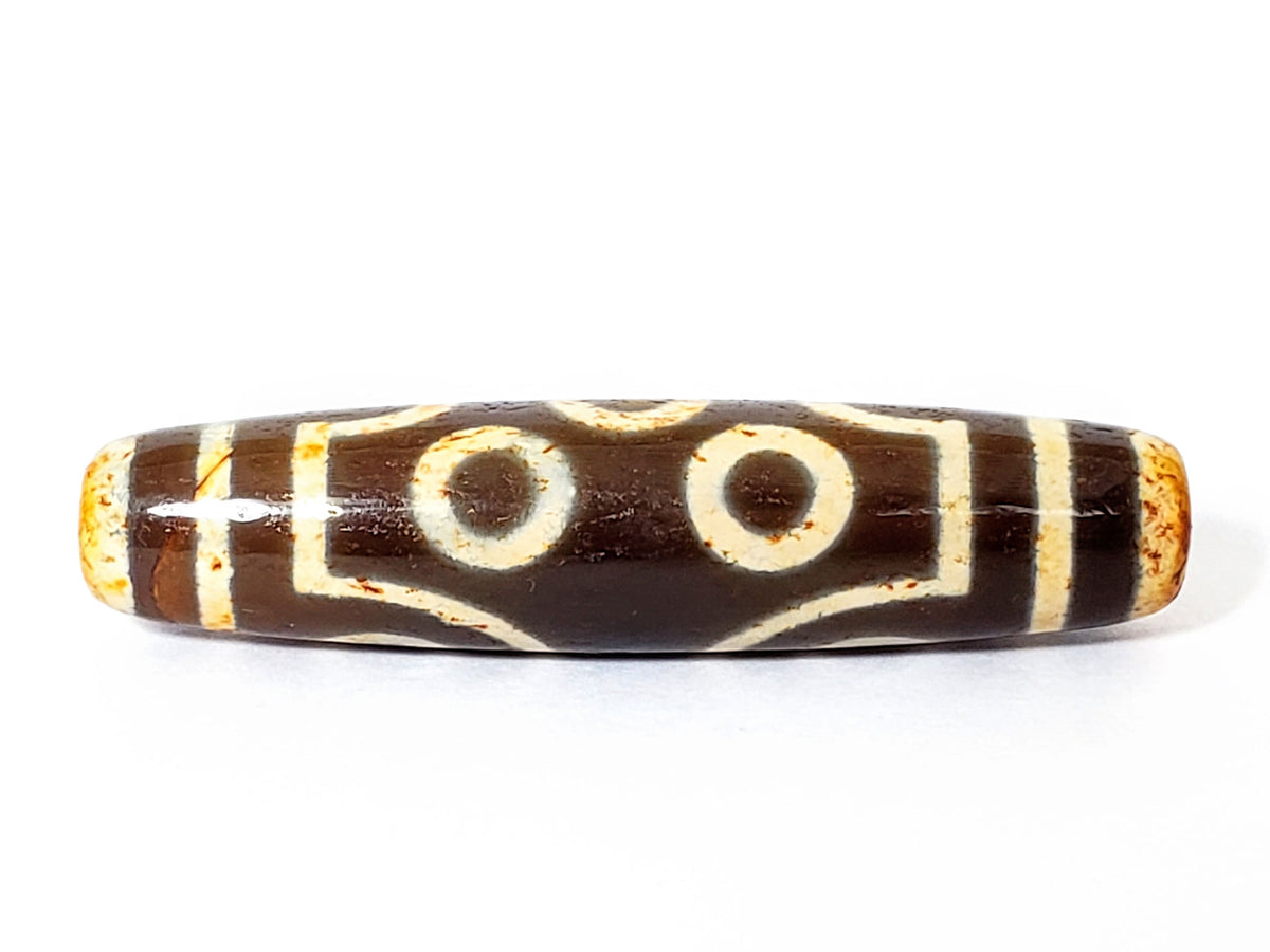 End view of ancient Two Eye Dzi — large drill hole, warm amber agate interior, cream pattern