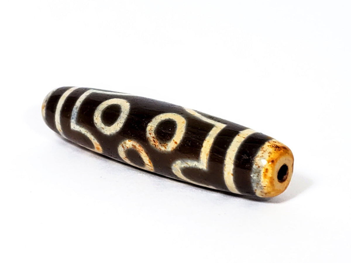 Ancient two-eye dzi bead, dark brown agate, cream white eye motifs, aged patina, visible drill hole, 500–800 years old