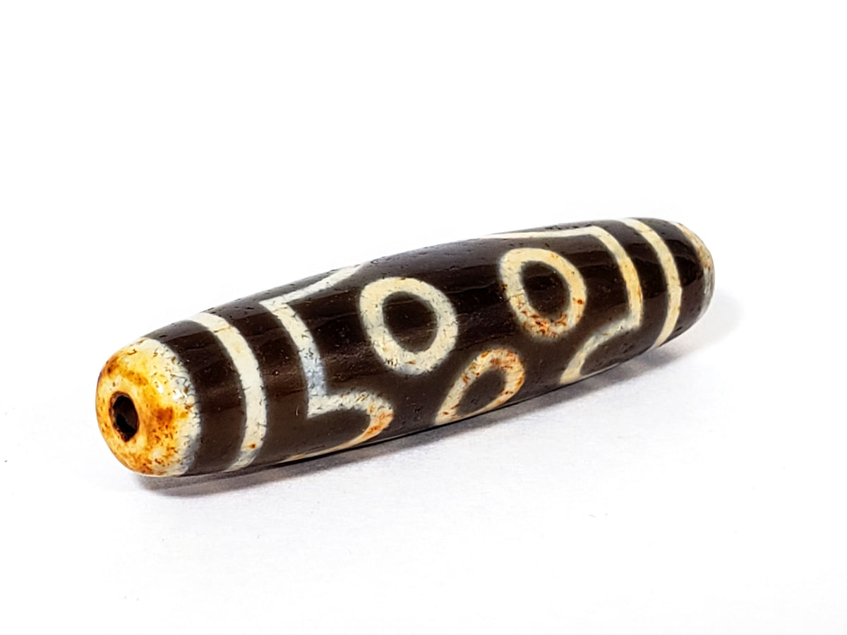 Ancient two-eye dzi bead, dark brown agate, cream eye motifs, aged patina, visible drill hole, bloodspots, 500–800 years old
