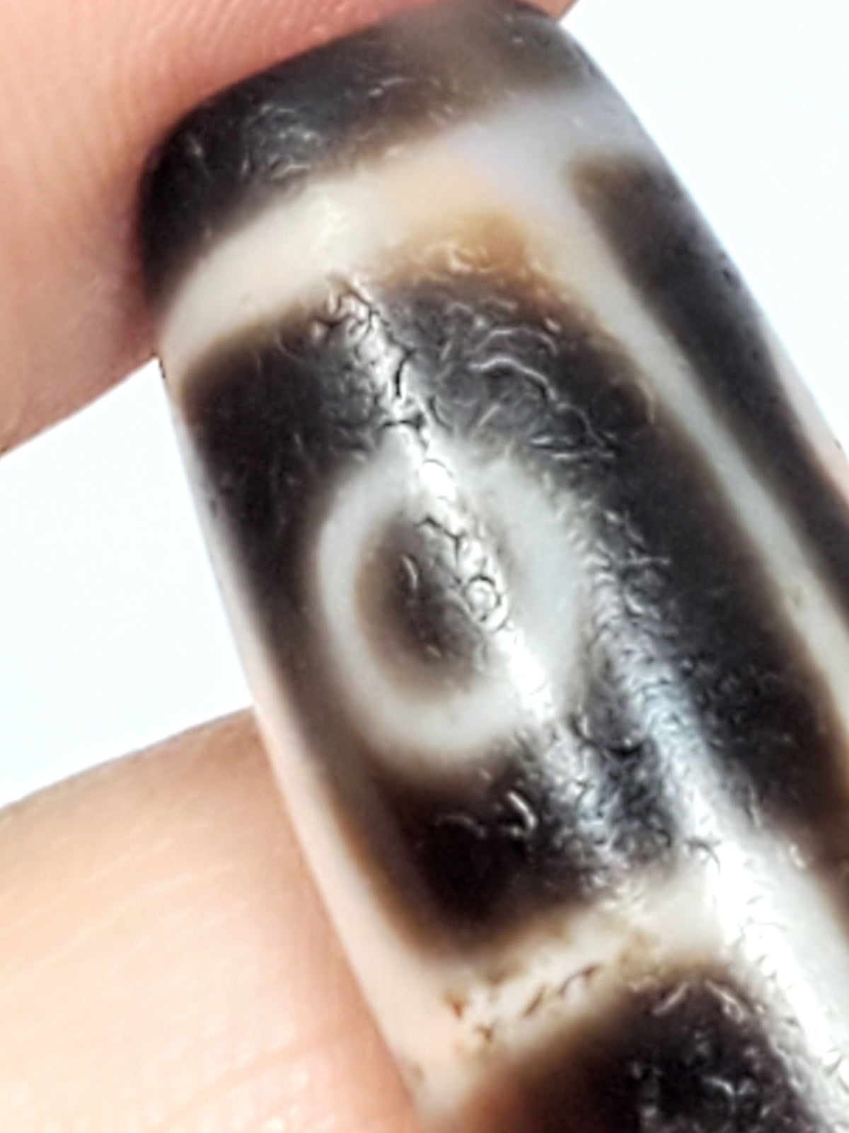 Six Eye Dzi bead, pale warm-brown agate with cinnabar bloodspots, 35mm, held in hand