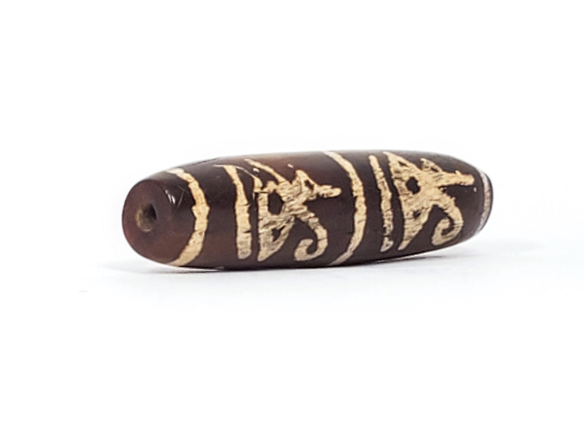 Ancient Tibetan dzi bead, dark brown agate, cream etched scarab and Ba bird motifs, visible drill hole, aged patina