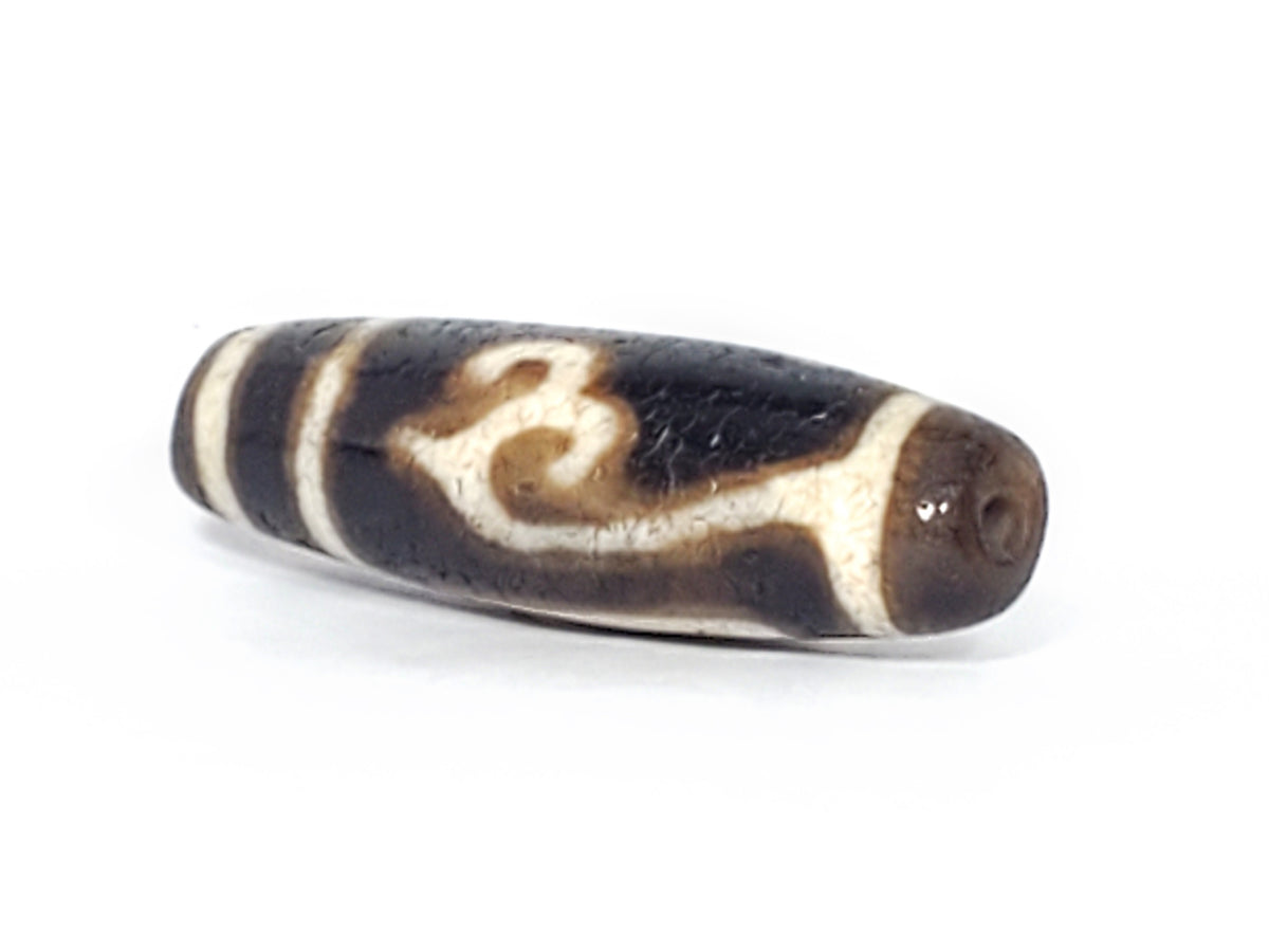 Ancient Tibetan Dzi bead Green Tara motif, dark agate, cream etched swirl pattern, visible drill hole, aged patina surface