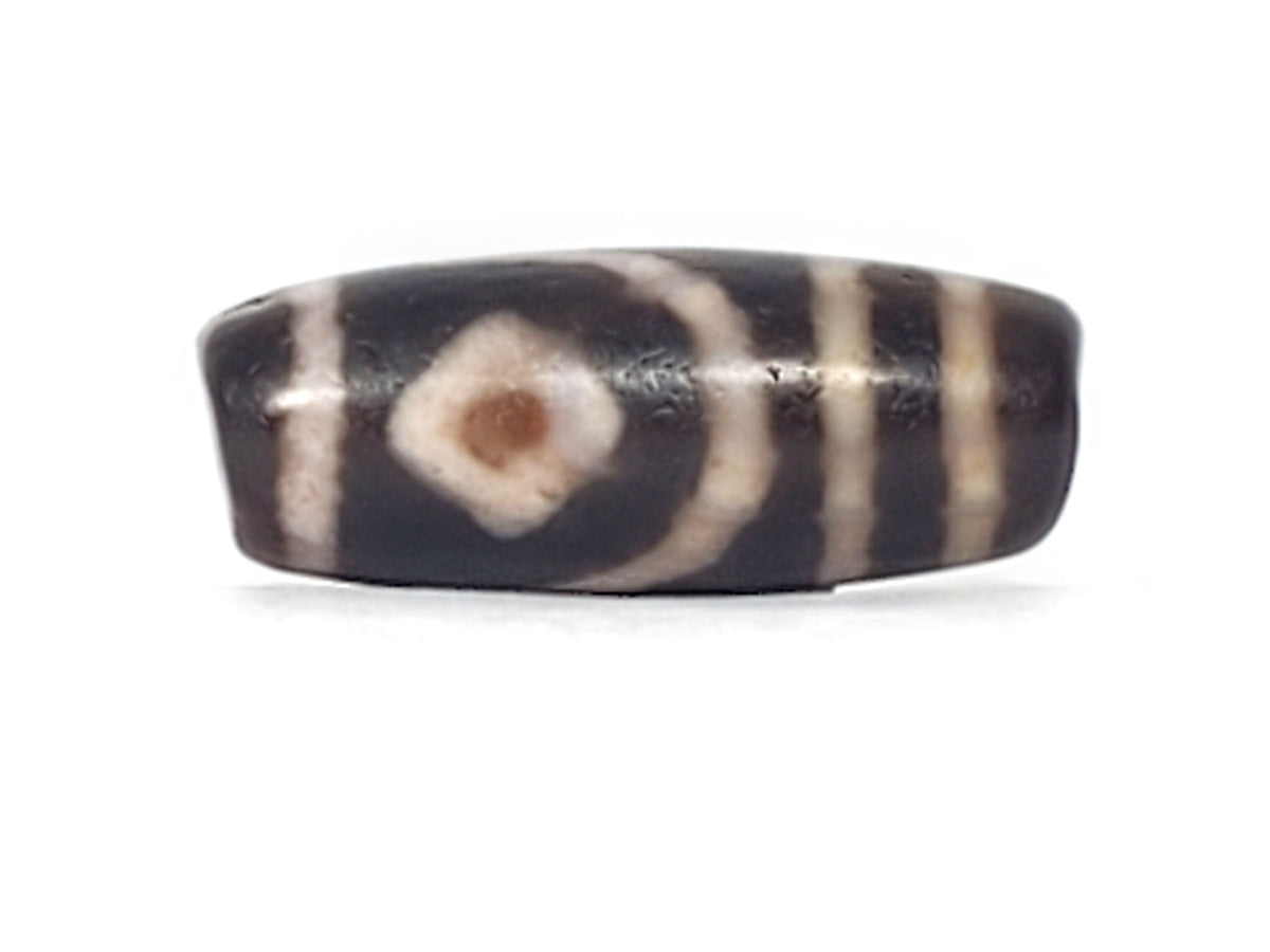 Macro: ancient dzi diamond eye — brown-black bloodspot at centre, heavy micro-crystalline crackle pitting, Anc-0426-2DE