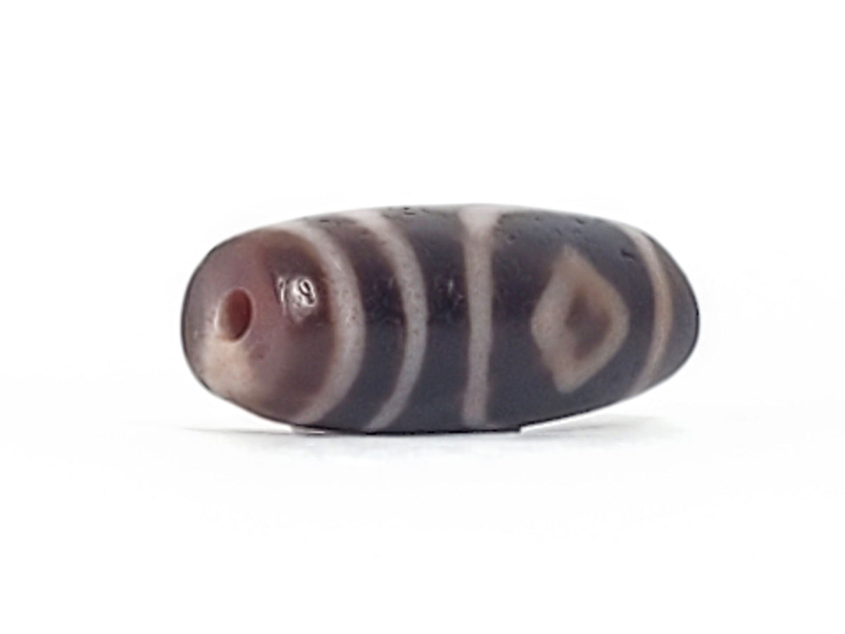 Macro: ancient dzi tip zone — black ground with crackle pitting and red-orange bloodspot dots, Anc-0426-2DE