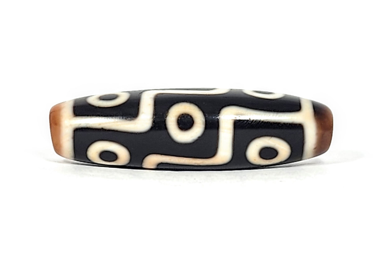 Antique Tibetan nine-eye dzi bead, black agate with cream white eye motifs and wave lines, brown patina tips, drilled ends