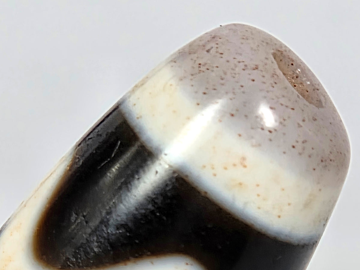 Antique Tibetan Dzi bead four activities motif black white agate bloodspots polished patina close-up