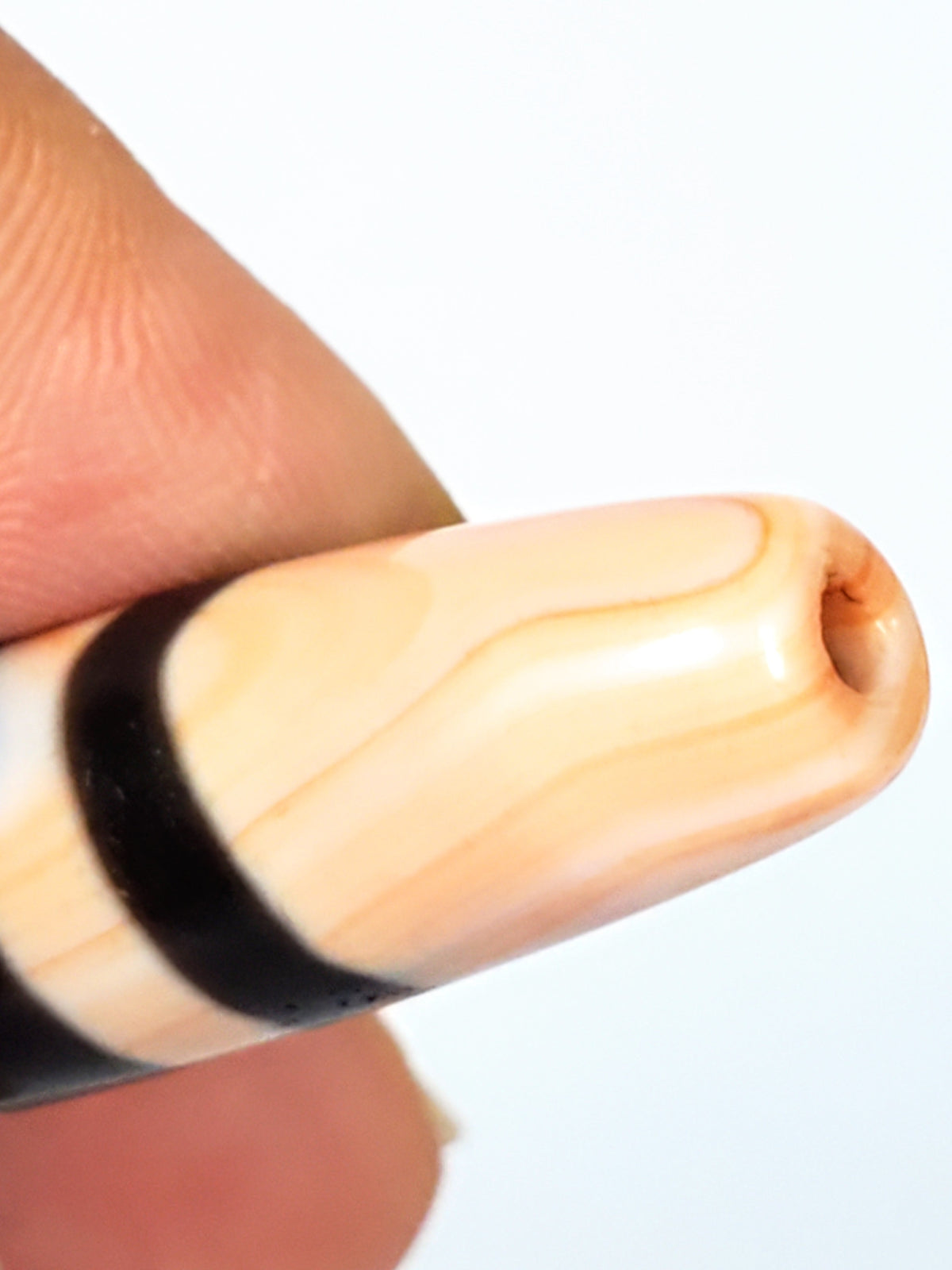 Antique Nepalese seven stripe chung dzi bead, cream black agate, wave pattern, drill hole visible, aged patina closeup