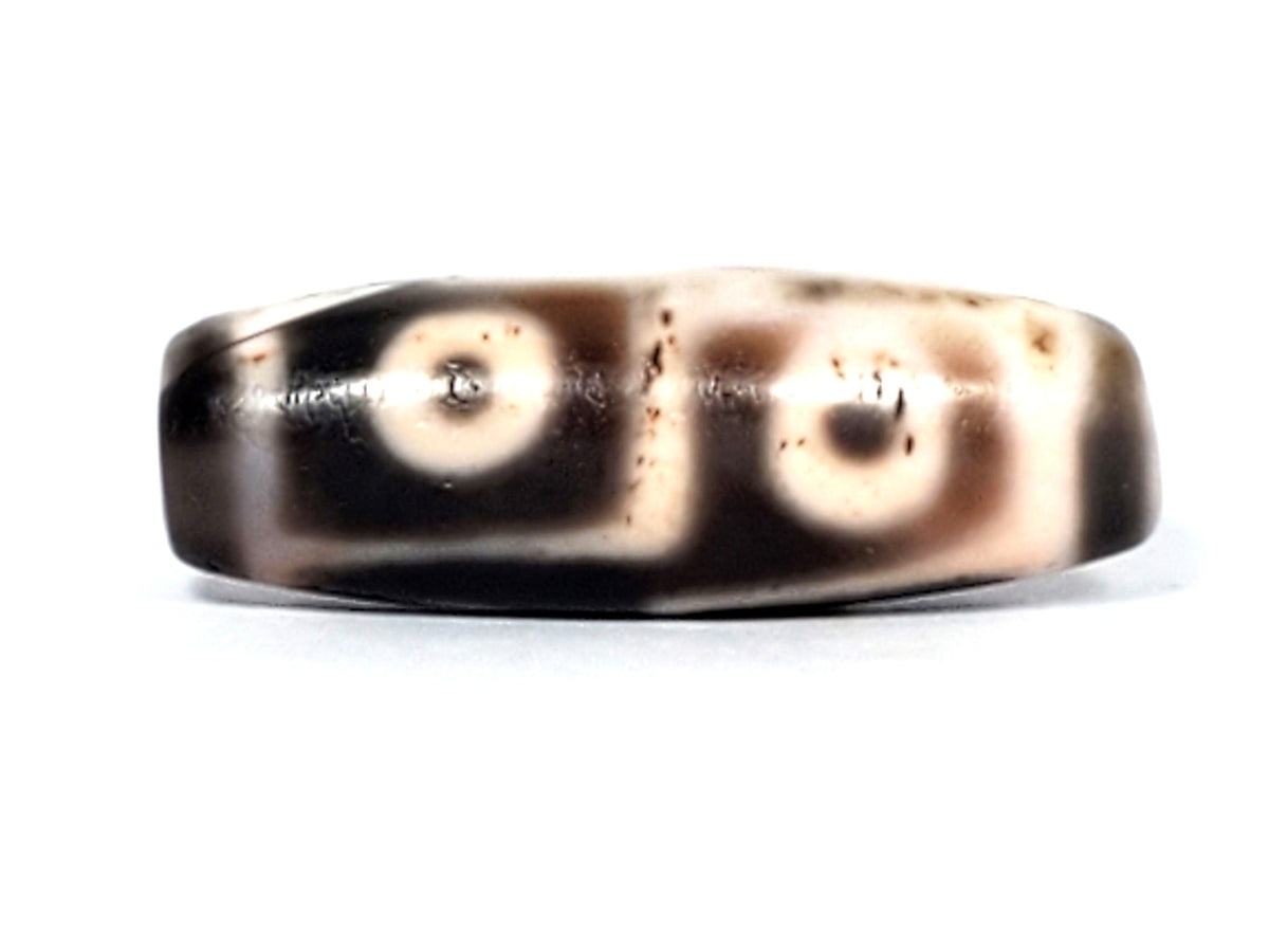 Six eye dzi bead, pale warm-brown agate with cinnabar bloodspots and natural patterning, 35mm polished barrel bead
