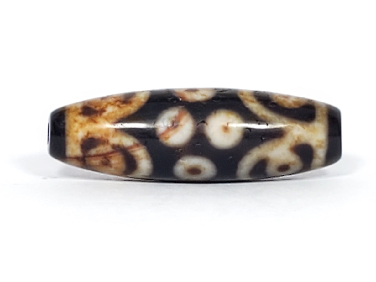 Antique Tibetan 15-eye dzi bead, dark agate, cream eye motifs, natural patina, bloodspots, visible drill hole, elongated barrel shape
