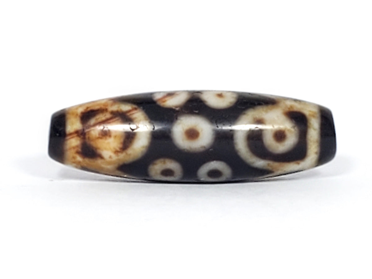 Antique Tibetan 15-eye dzi bead, dark agate, white eye motifs, brown patina, aged surface, elongated barrel shape