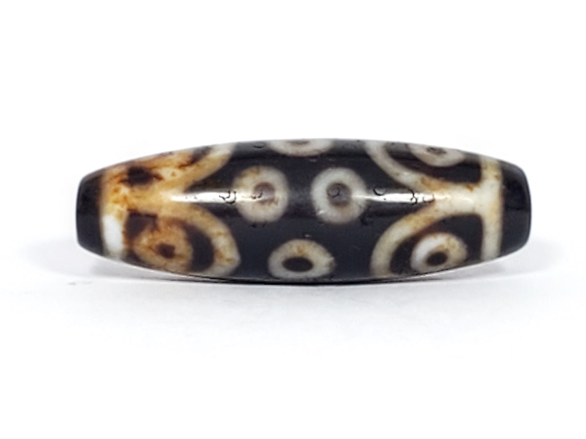 Antique Tibetan 15-eye dzi bead, dark agate, white eye motifs, brown patina, aged surface, oval barrel shape