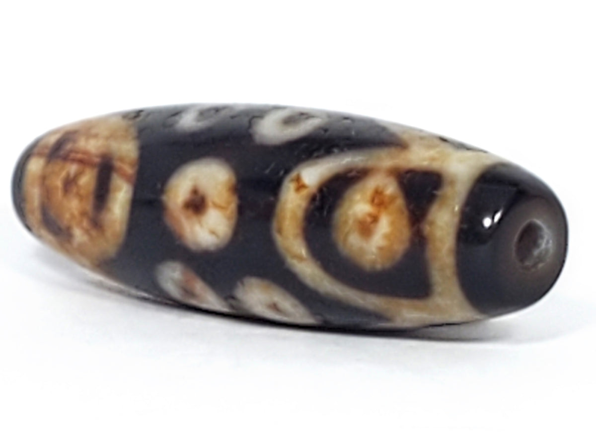 Antique Tibetan 15-eye dzi bead, dark agate, cream eye motifs, natural patina, visible drill hole, bloodspots