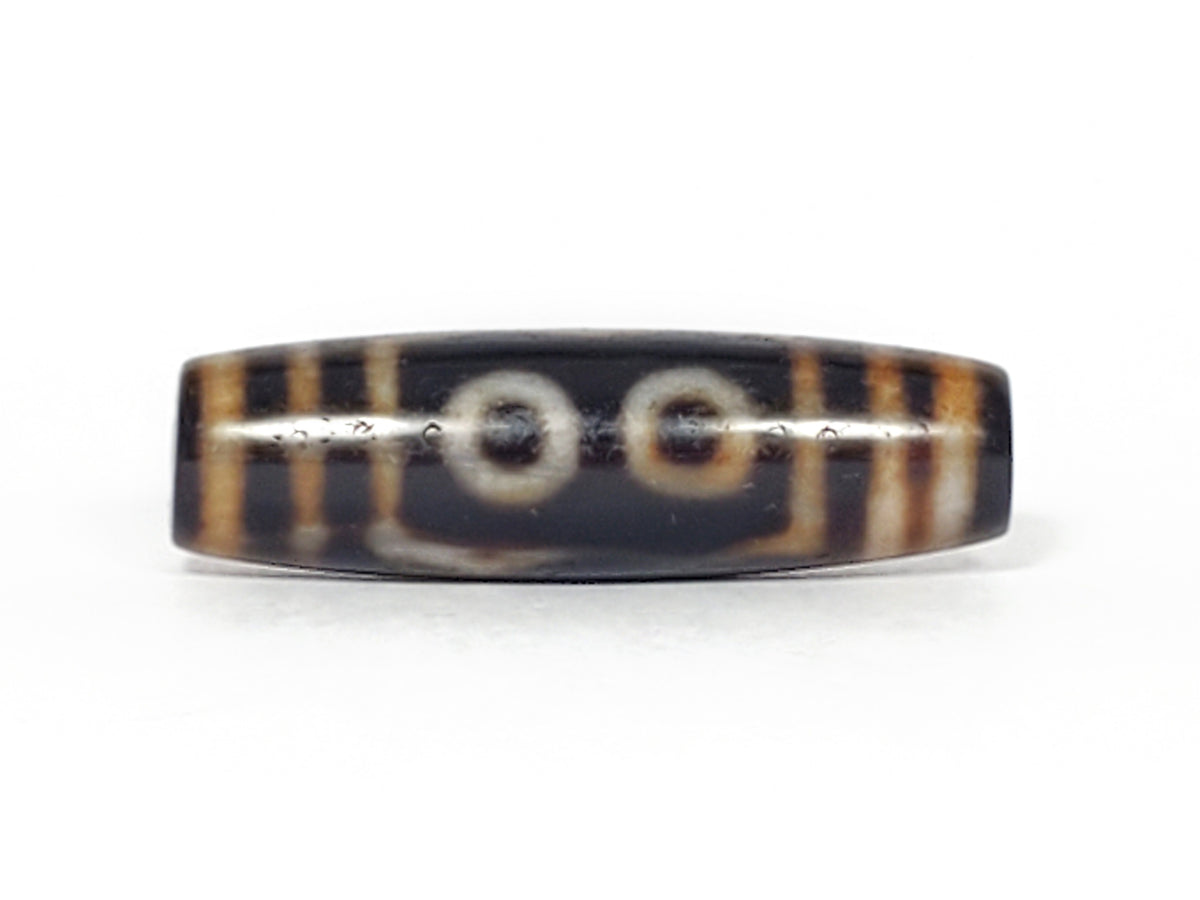 Antique Tibetan dzi bead, two-eye motif, dark agate, white eye circles, brown stripe patterning, aged patina, visible drill hole