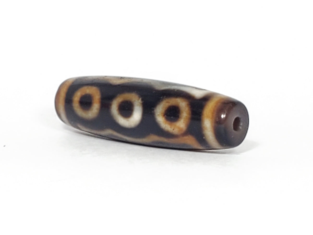 Antique five-eye dzi bead, dark agate, white eye motifs, brown patina, visible drill hole, aged surface texture