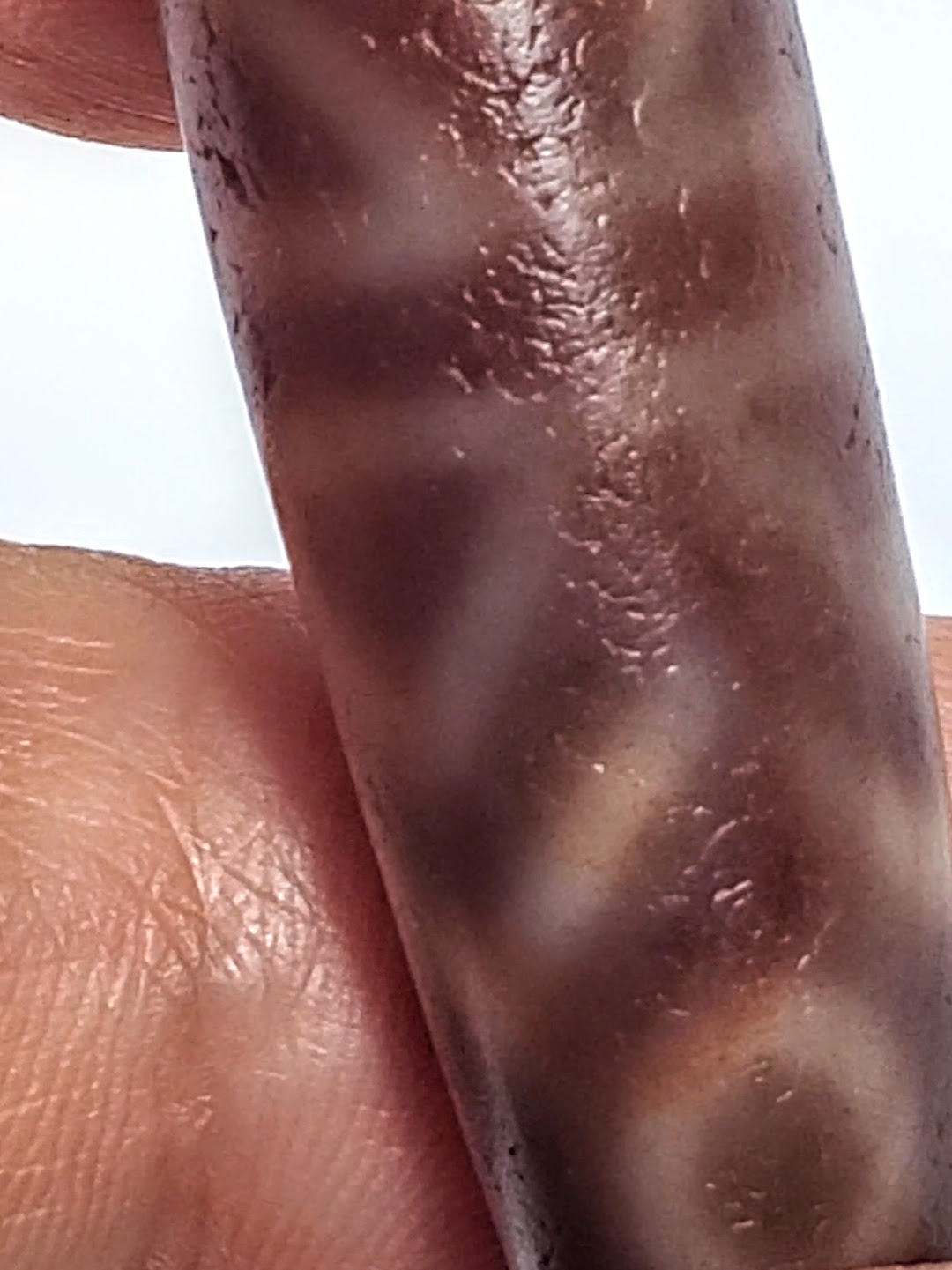 Antique dzi bead six-eye tiger tooth motif dark agate bloodspots aged patina etched surface close-up hand held
