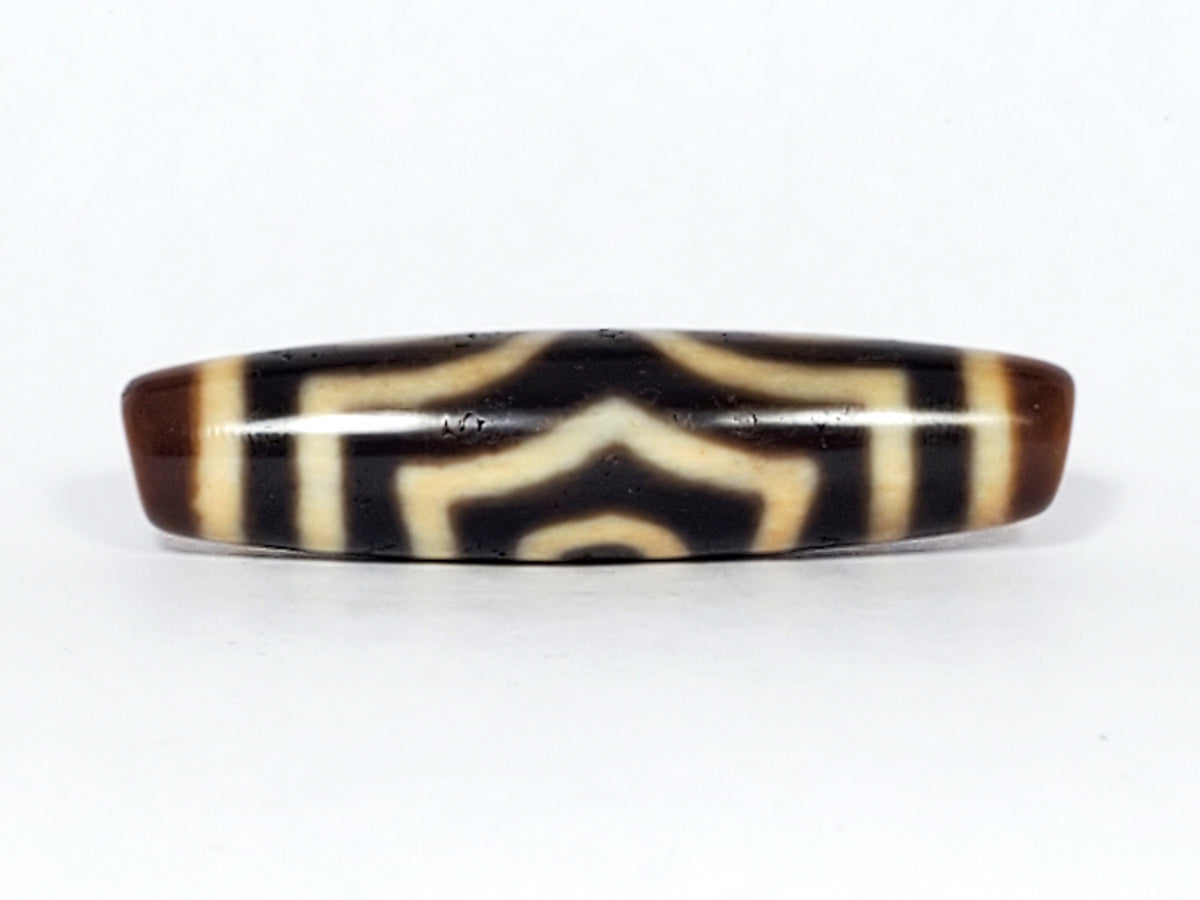 Antique three-eye dzi bead, dark brown agate, cream stripe motif, elongated barrel shape, aged patina, visible drill holes