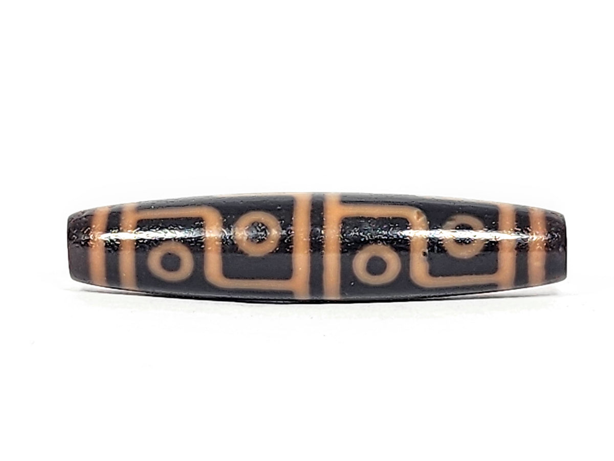 Antique Tibetan 12-eye dzi bead, dark agate with cream etched eye motifs and geometric patterns, elongated barrel shape