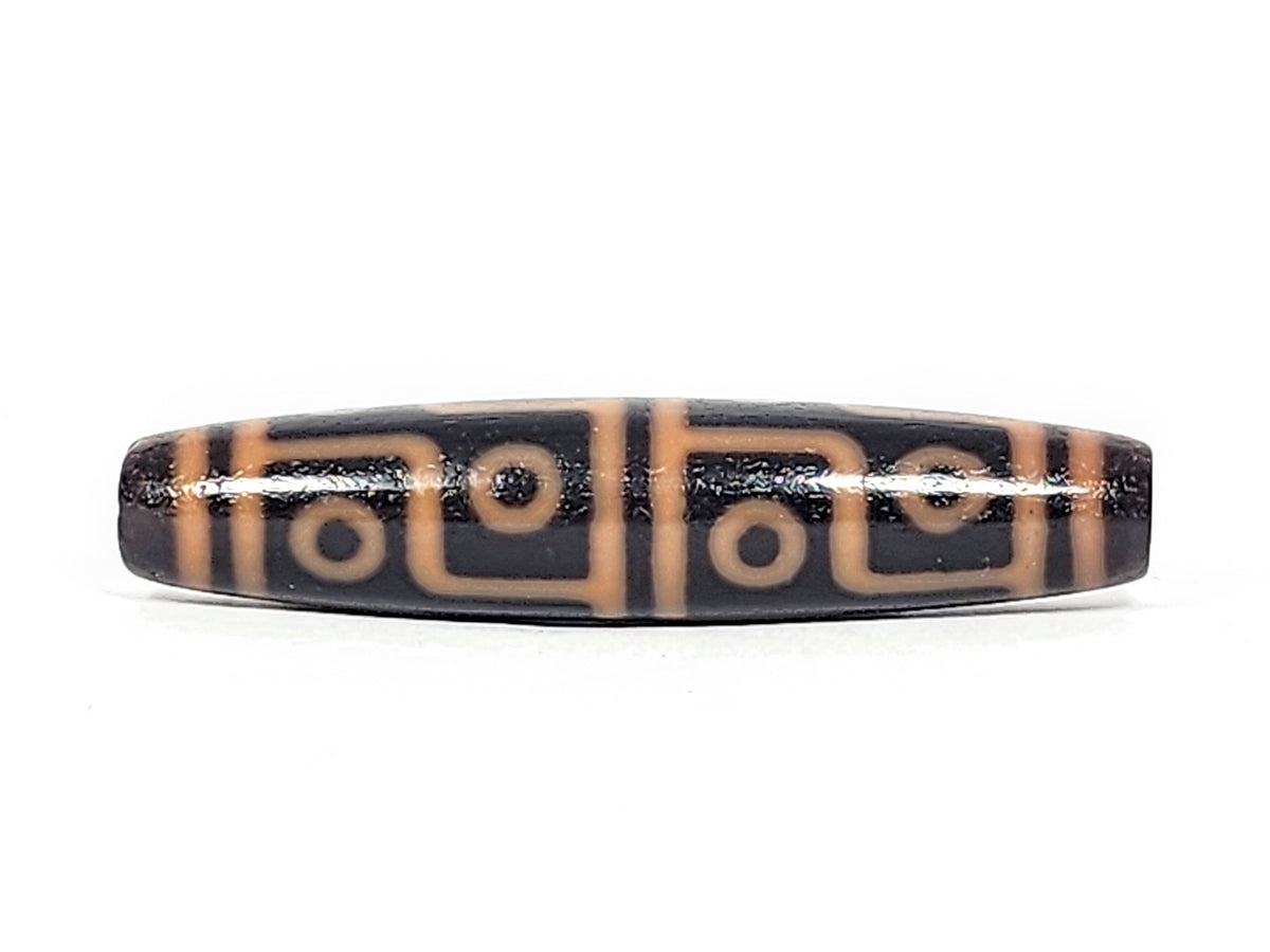 Antique Tibetan 12-eye dzi bead, dark agate with tan eye and geometric motifs, glossy patina, elongated barrel shape