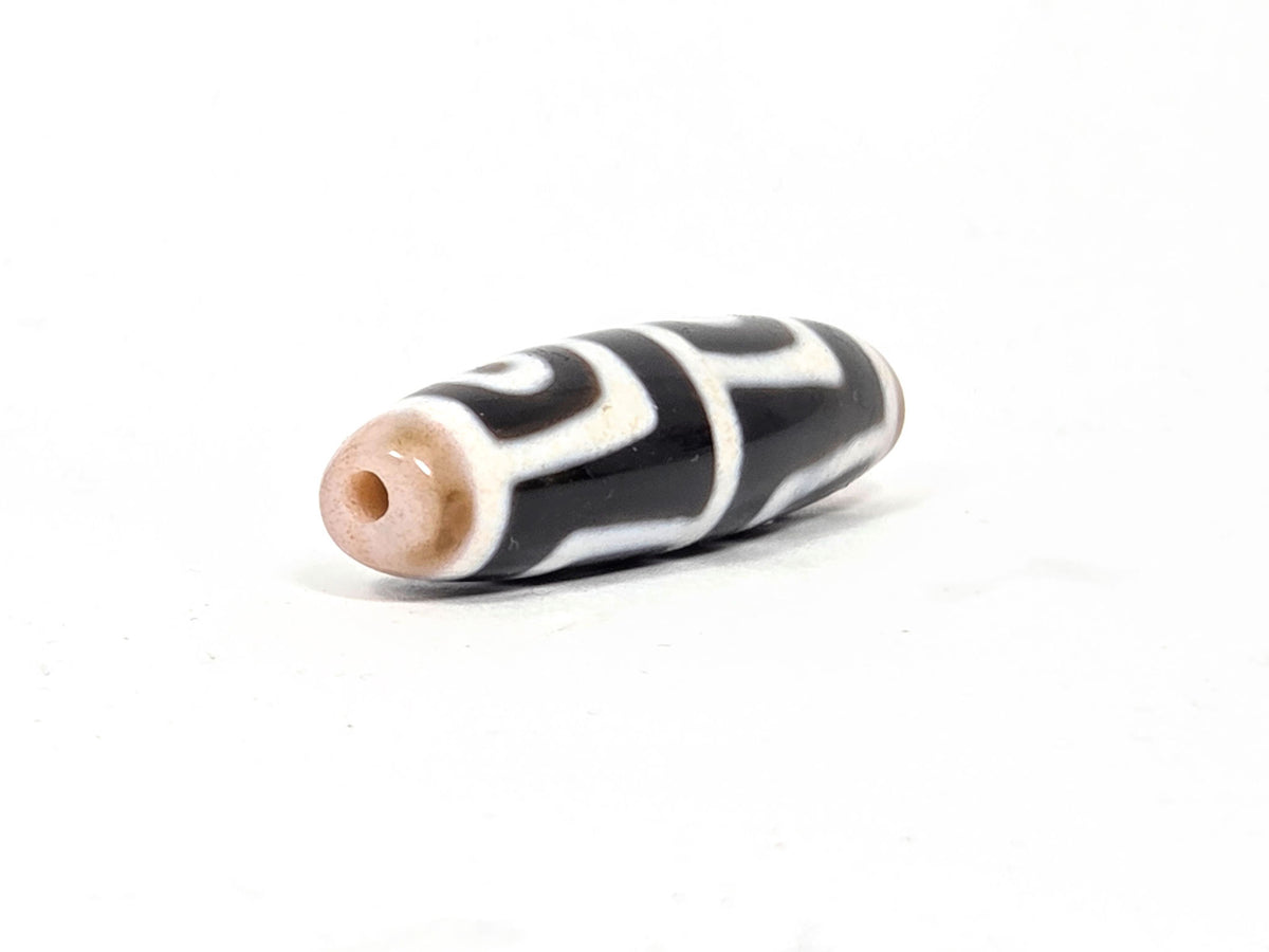 At-042626-4E3 End A, warm sandy-tan end cap, centred drill hole, pitch-black body, white lines, unretouched