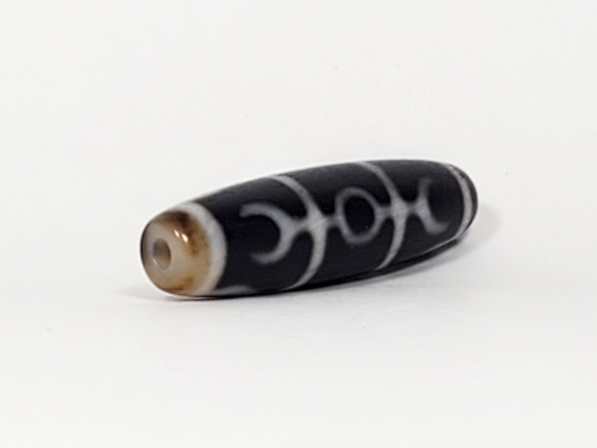 Antique black agate dzi bead, Guru Rinpoche scepter motif, white etched pattern, visible drill hole, natural patina, bloodspots
