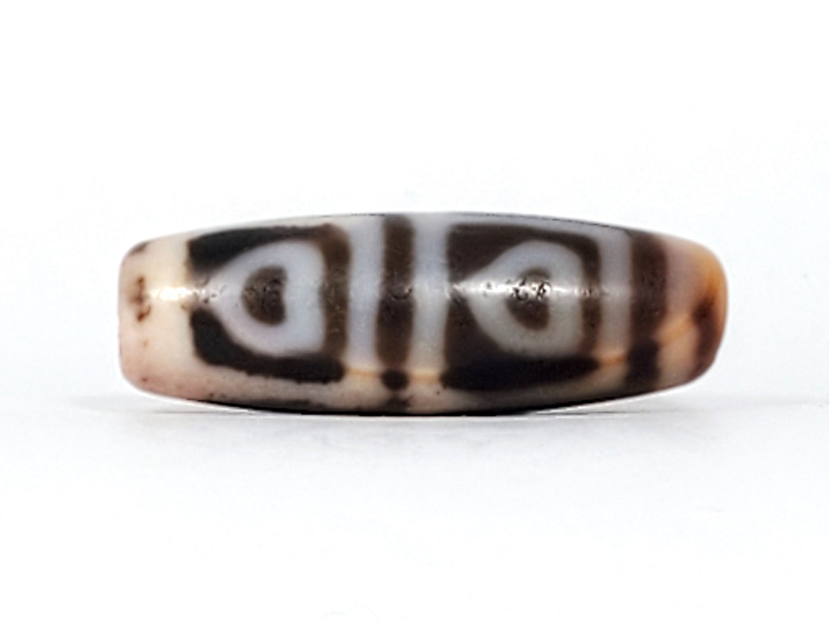 Another end cap of antique Four Leaf Bodhi dzi bead At-101624-FLB, warm brown agate tip, centred drill hole, compact barrel body, amber ground, unretouched photography