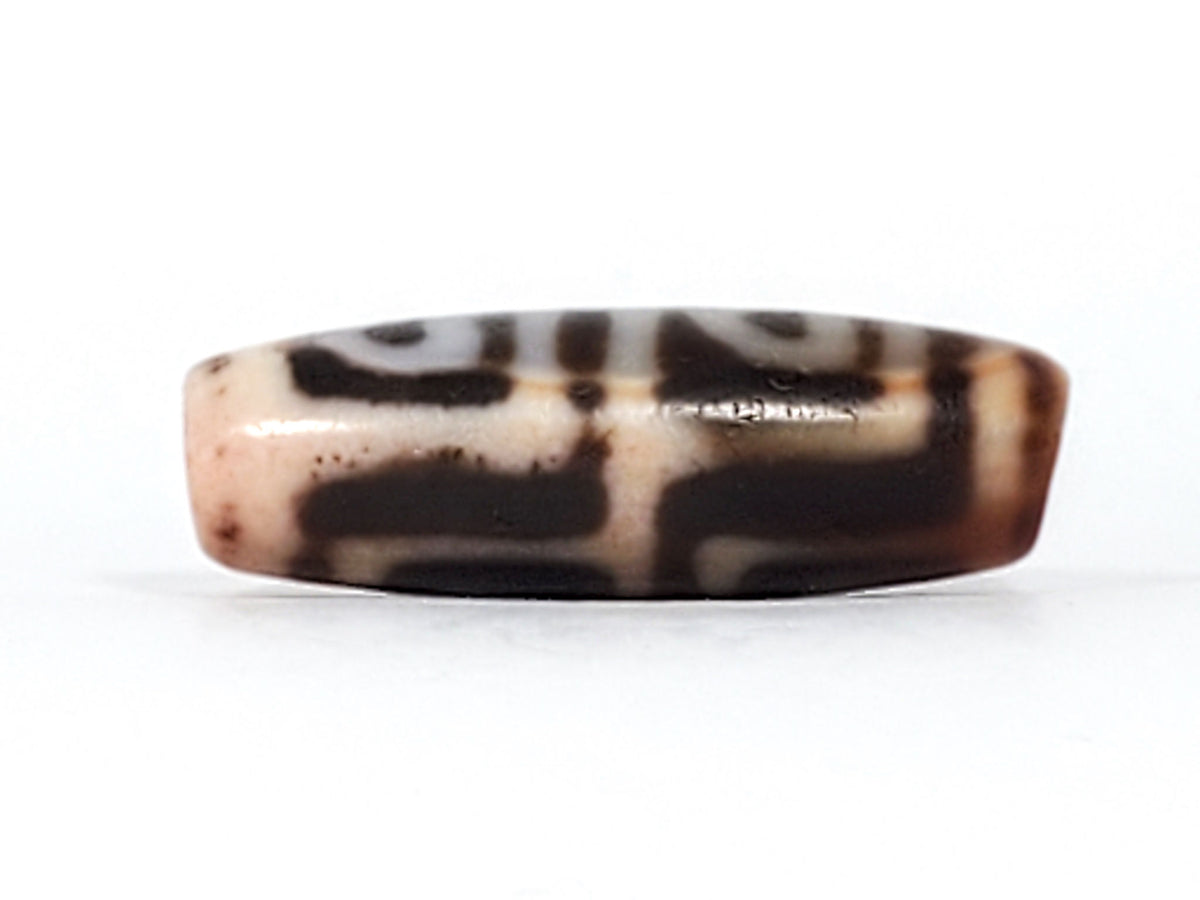 Close detail of antique Four Leaf Bodhi dzi At-101624-FLB showing bloodspot cinnabar inclusions on amber-brown agate surface, authentic age markers, unretouched photography