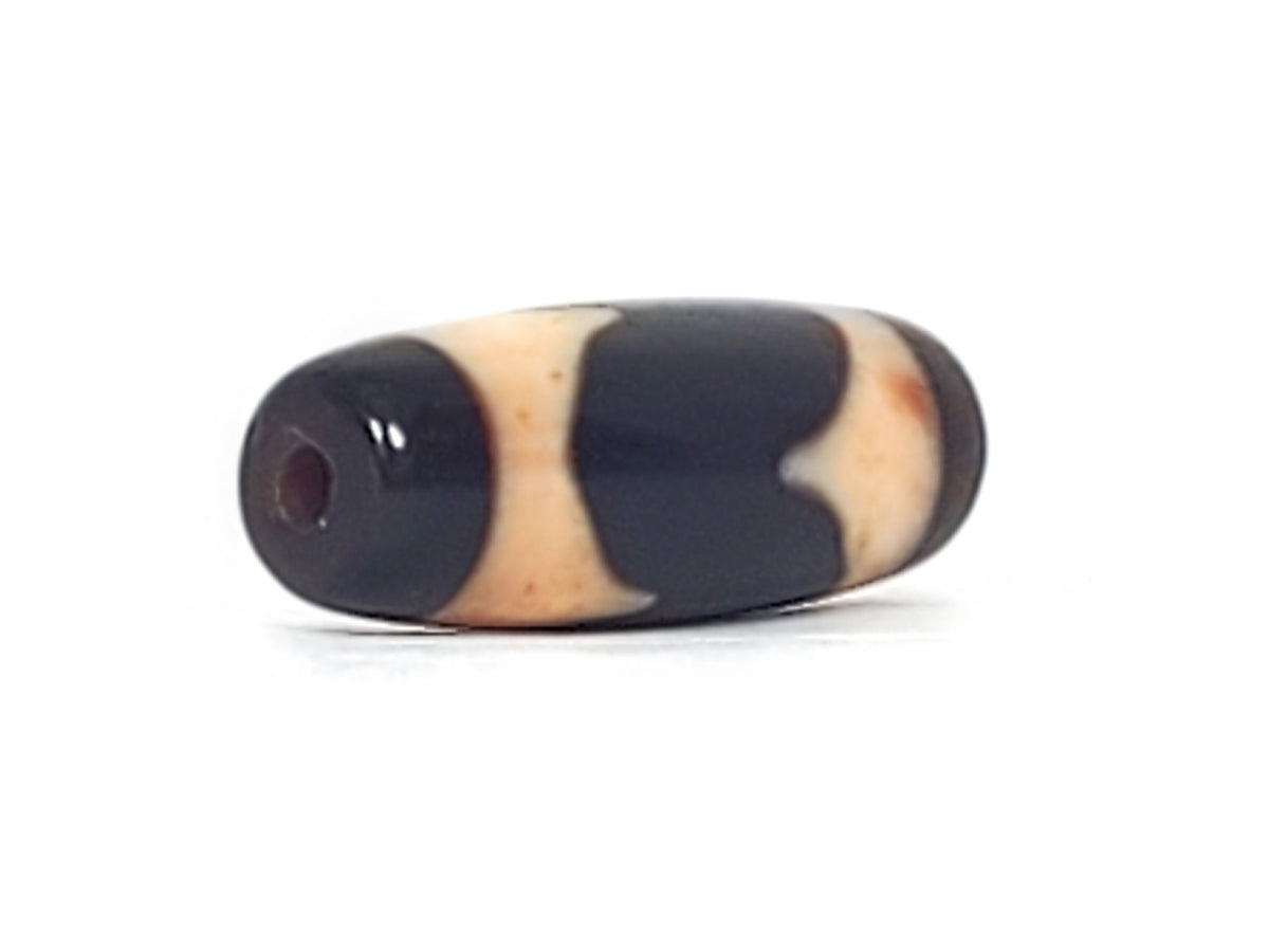 Opposite end cap of antique Tasso dzi At-092924-TaBS2, pitch-black agate tip, drill hole centred, cream Tasso zones with bloodspot inclusions visible, 28.7mm × 11.2mm