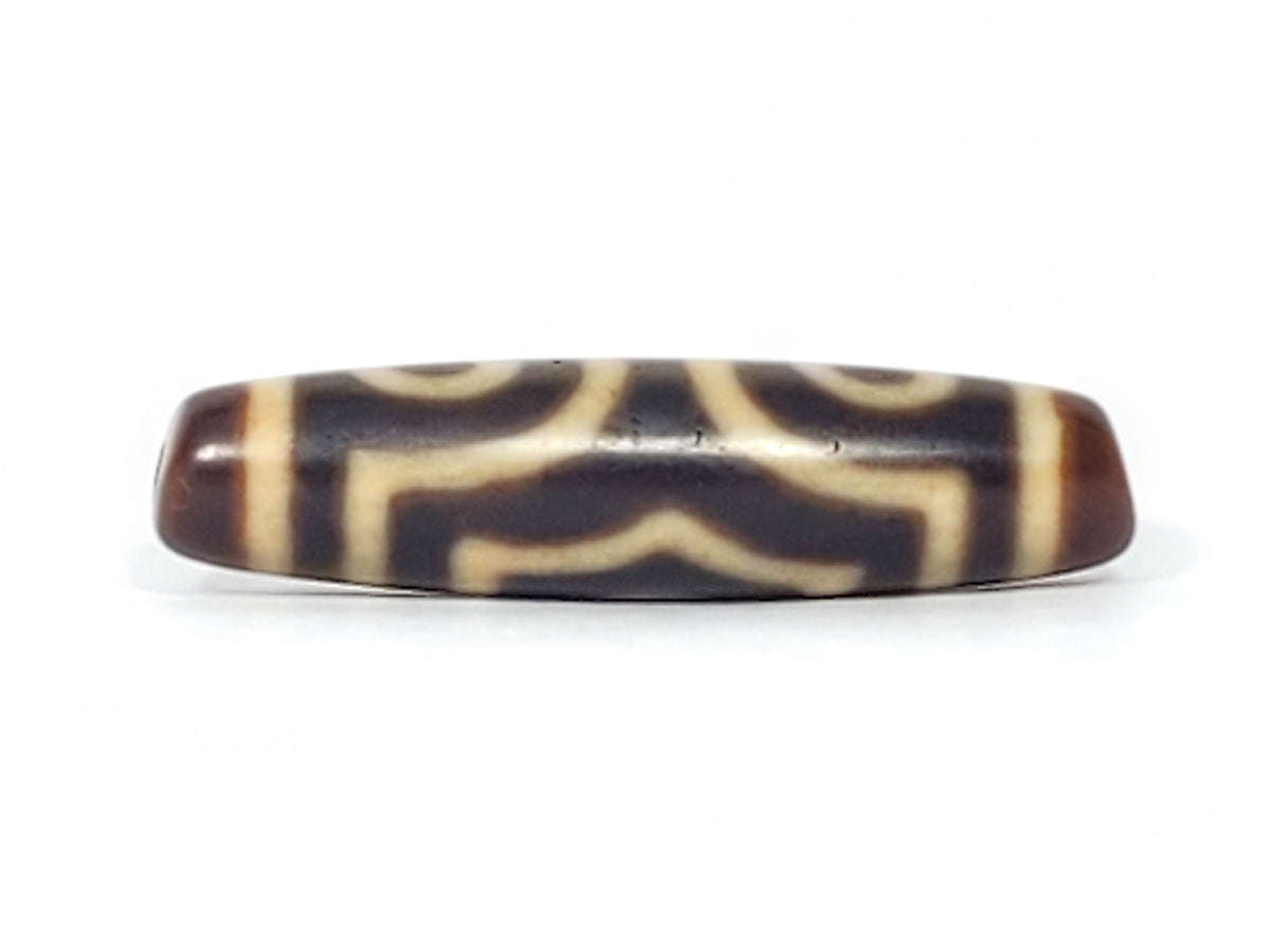 Antique Tibetan three-eye dzi bead, dark agate with cream etched eye motifs and wave pattern, aged patina, elongated barrel shape