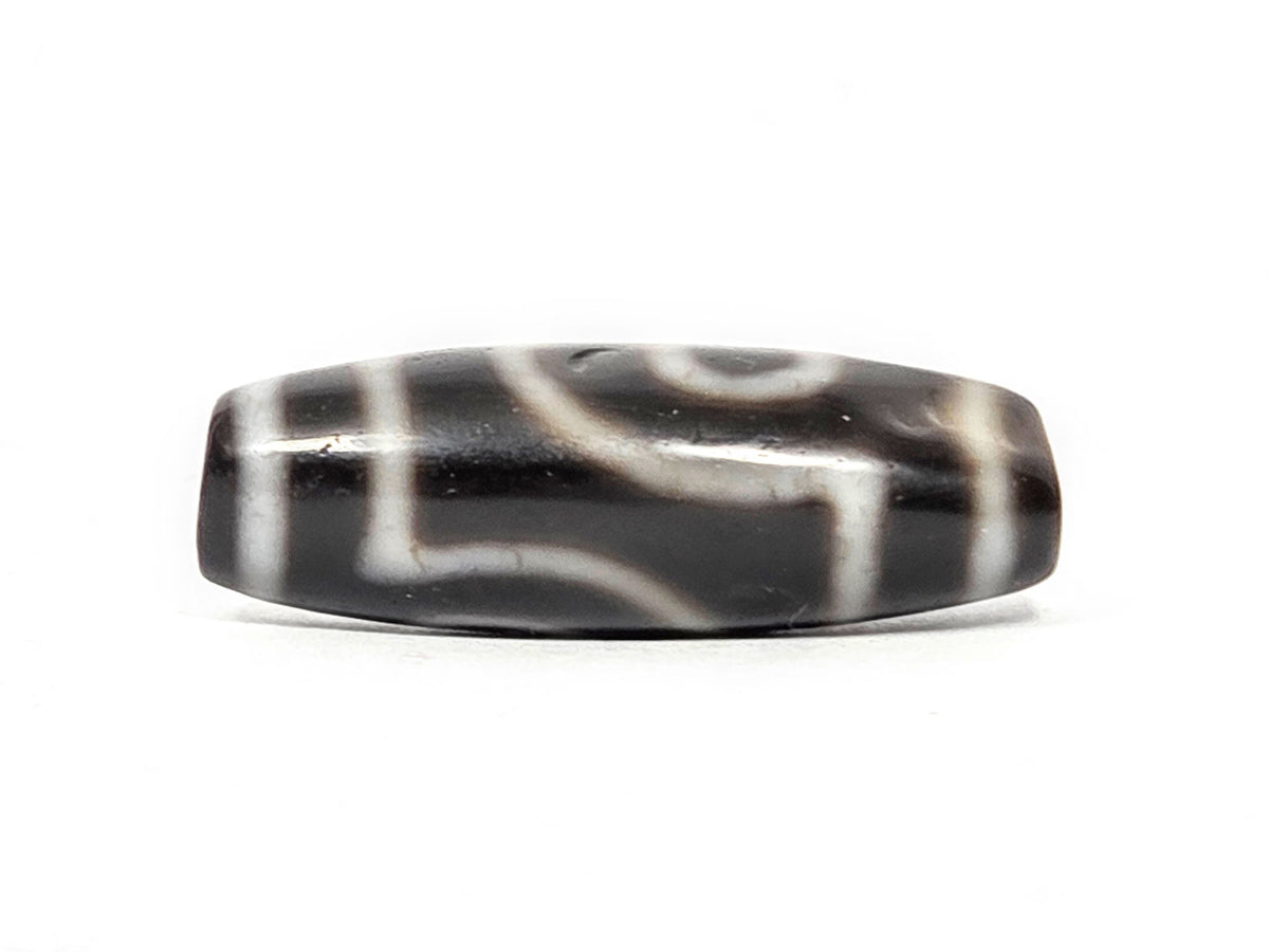 Alternate angle of antique two eye dzi At-033126-2E4, cream scroll wave motif on pitch-black agate, medicine dig face from different rotation, 37.3mm, unretouched