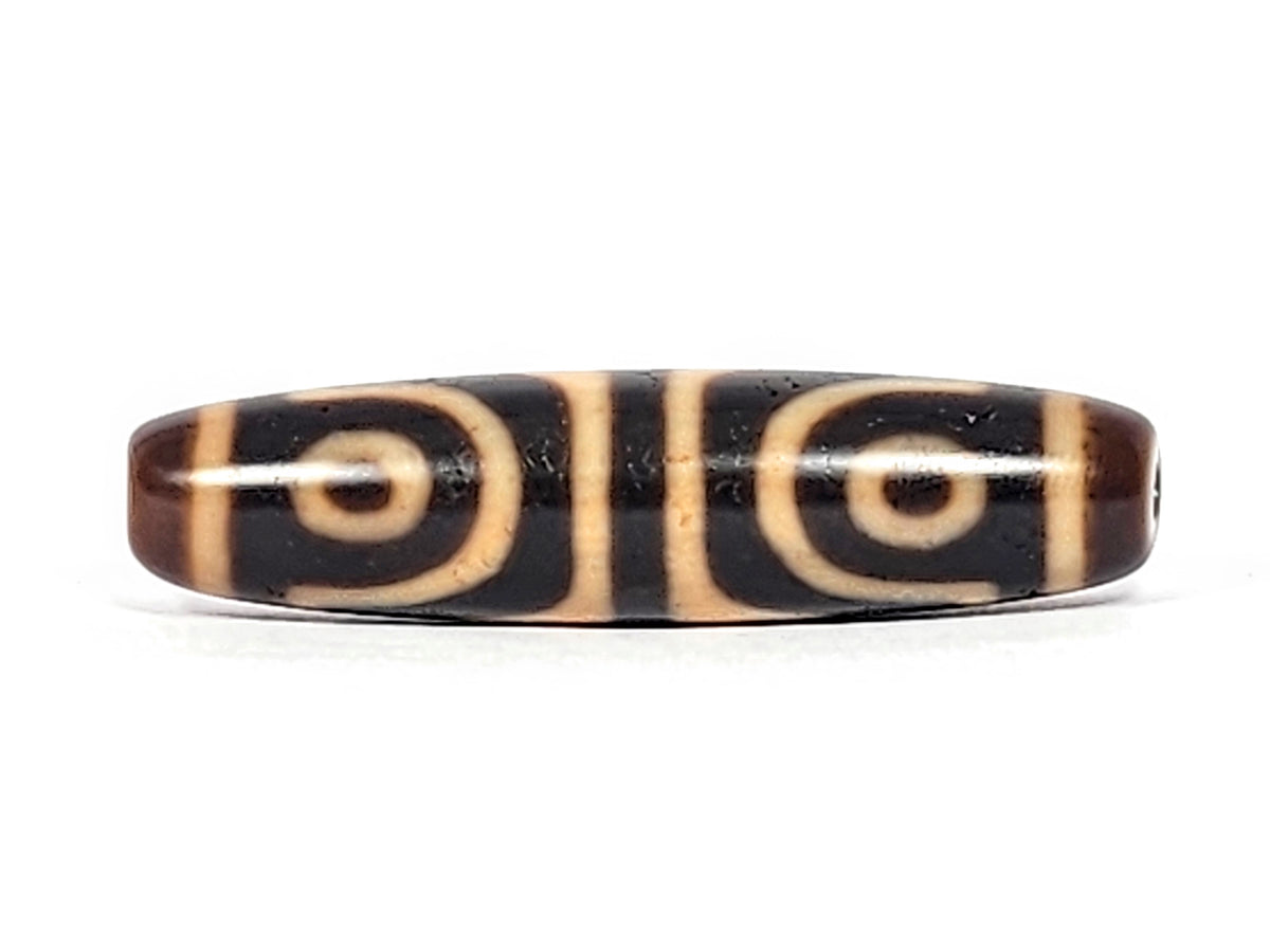 Antique Tibetan dzi bead, four-eye tiger tooth motif, dark agate, cream swirl patterns, aged patina, oval barrel shape