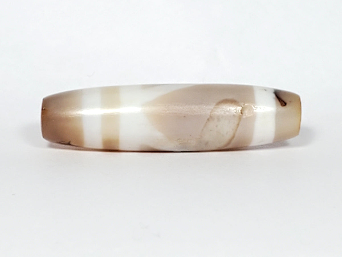 Ancient double mountain motif dzi bead, banded agate, cream and tan striping, elongated barrel shape, visible drill hole, natural patina