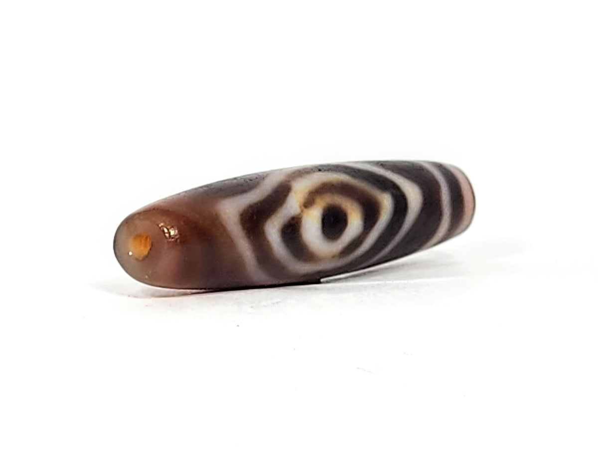 Antique eye-in-eye heaven gate dzi — angled view, Eye-in-Eye with amber toning, drill hole at narrow right tip, At-0426-EIE