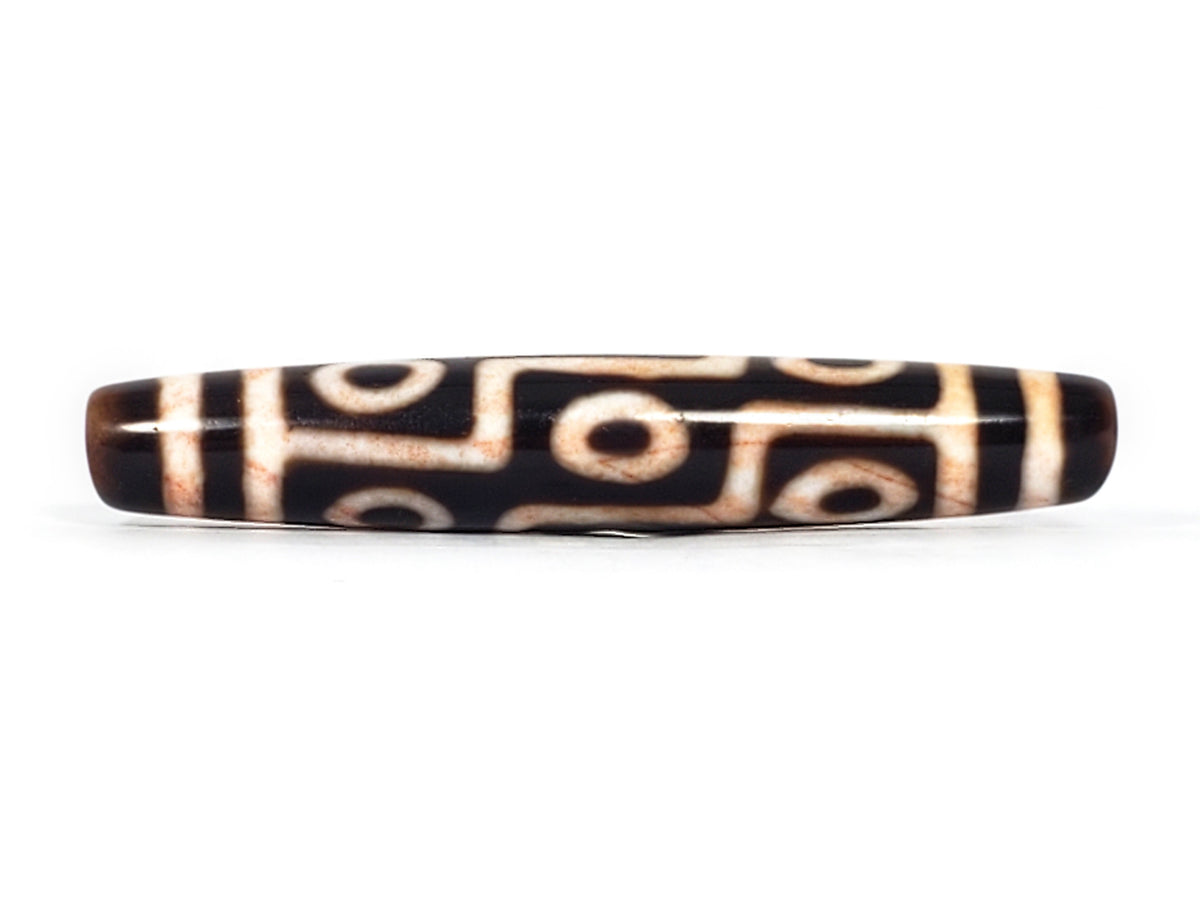 Antique Tibetan nine-eye dzi bead, dark agate with white eye motifs, red bloodspots, aged patina, elongated barrel shape