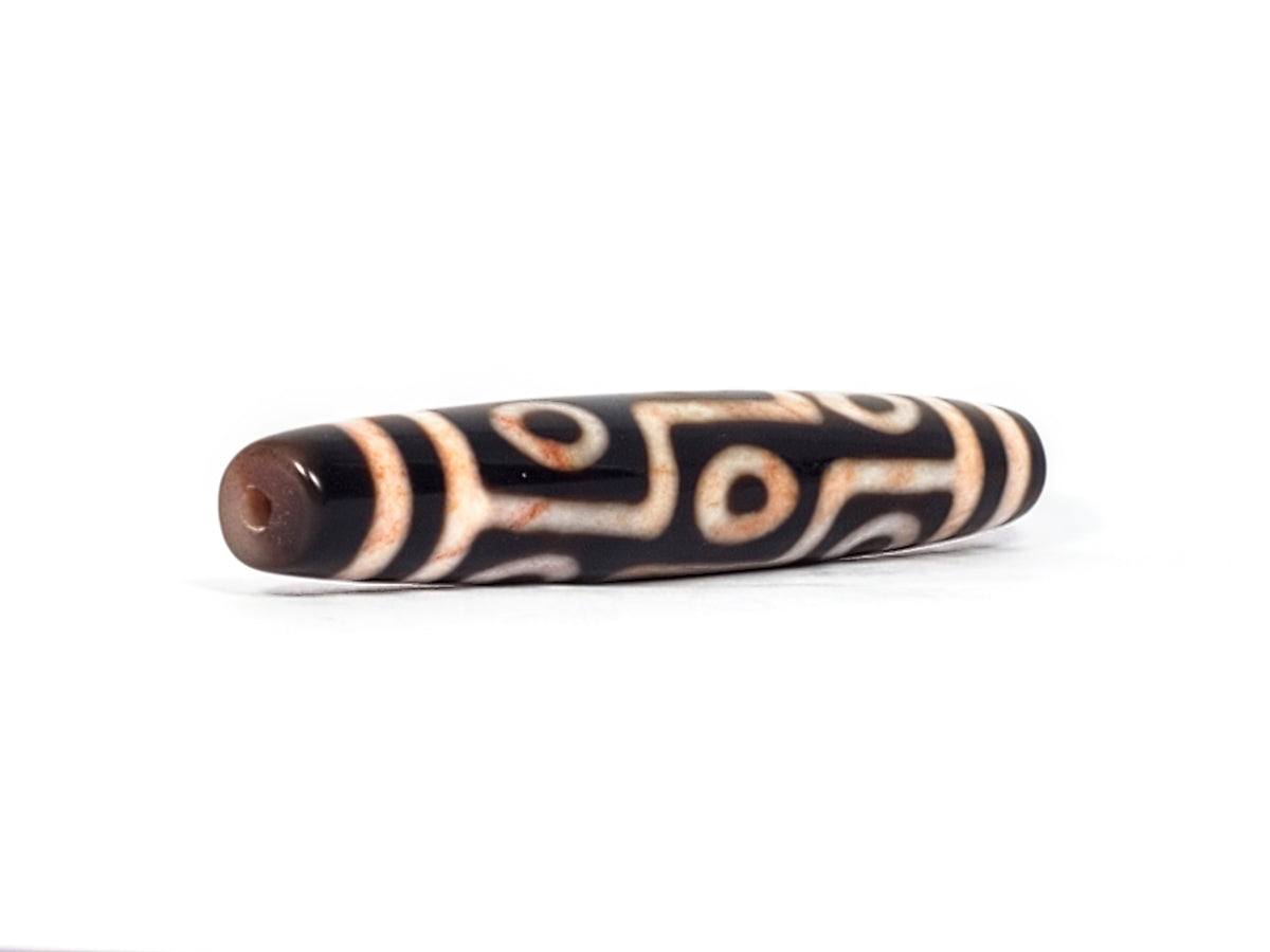 Antique Tibetan nine-eye dzi bead, black agate, cream white eye motifs, visible bloodspots, patina, drilled end hole