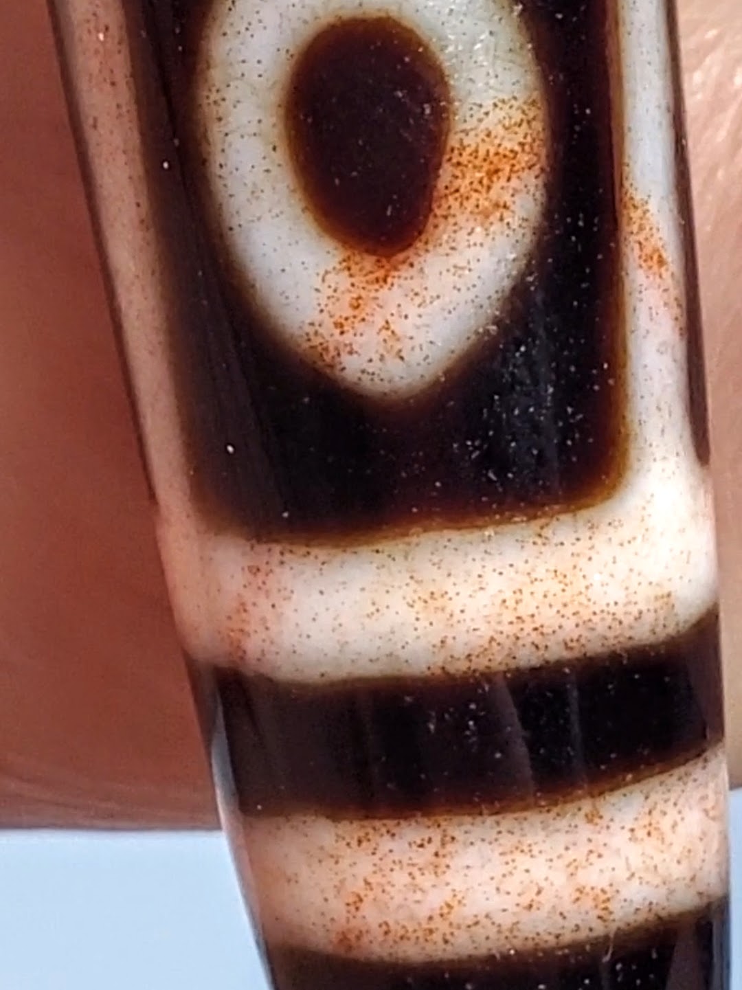 Antique Tibetan nine-eye dzi bead, cream agate with dark brown etched eyes, visible bloodspots and aged patina surface
