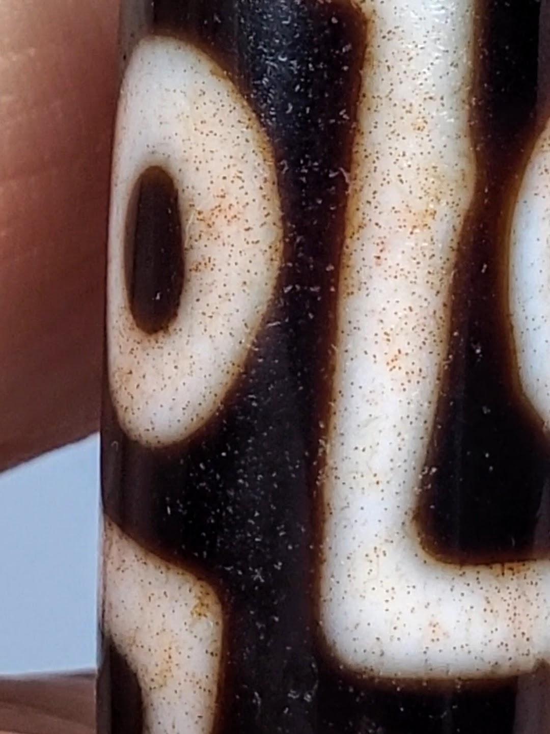 Antique Tibetan nine-eye dzi bead, cream agate with dark brown eye motifs, heavy cinnabar bloodspots, aged surface texture