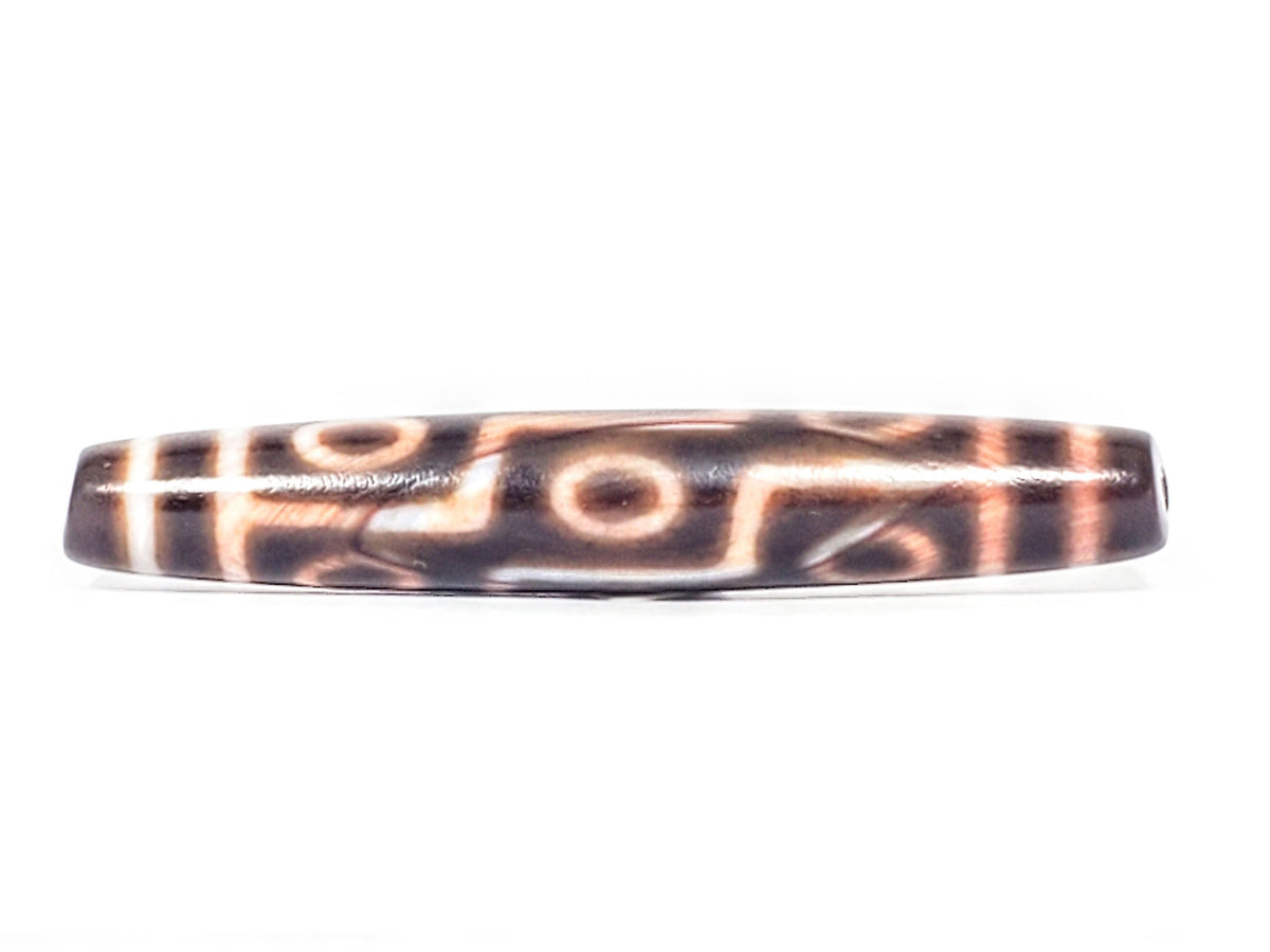 At-062926-9EBS angled drill-end view, spindle barrel form, nine eye motif, deep dark brown agate, unretouched