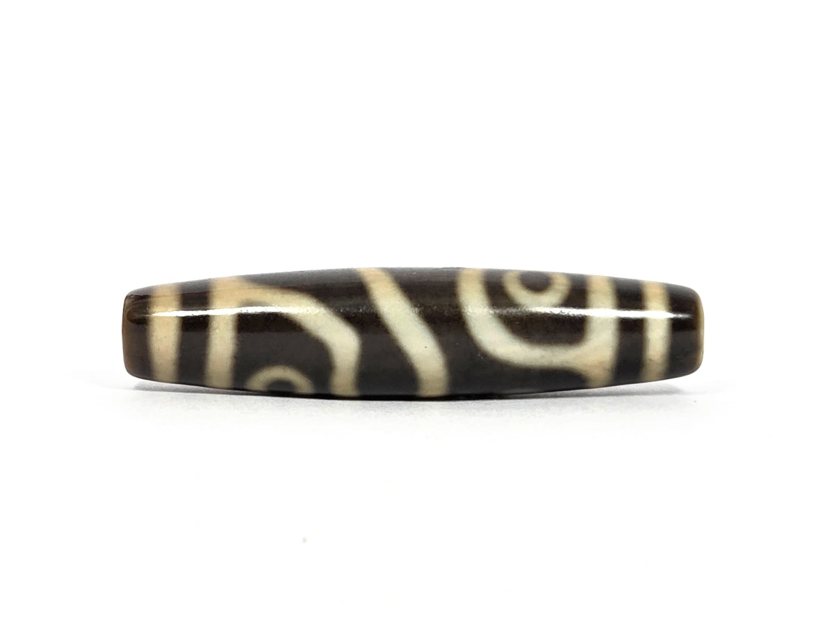 Fourth face of new four eye variant dzi bead N-102526-4EVS showing two cream eyes side by side — one in a framed panel near the left end, one smaller oval eye toward the right — divided by a curved cream line, on dark brown to black agate
