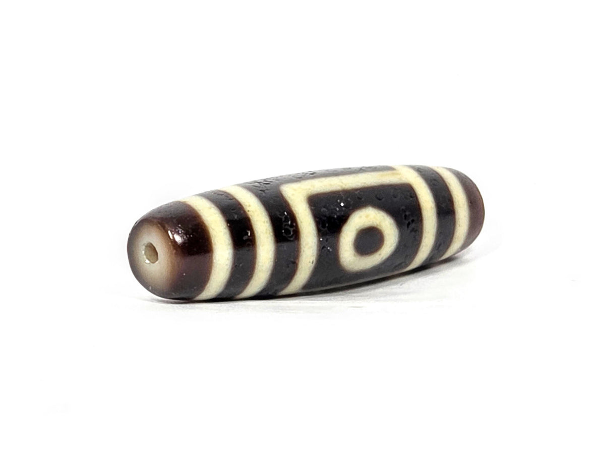 Two-eye dzi bead, dark brown and black agate with cream stripes, polished surface, drilled holes visible