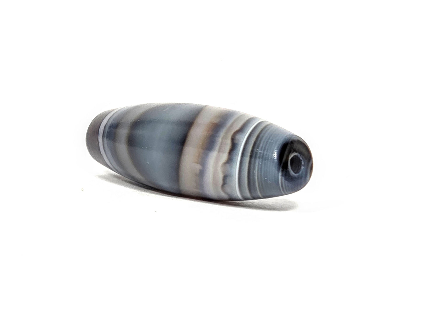 N-N-080926-1E6 natural one eye dzi bead 50.5×15.8mm, opposite angled end view showing secondary naturally-formed eye at drill opening within warm brown oval, unretouched