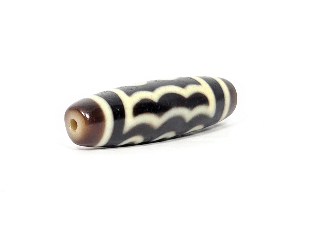 Five-eye dzi bead, dark brown agate, wave motif, cream white lines, visible drill hole, elongated barrel shape, 41mm