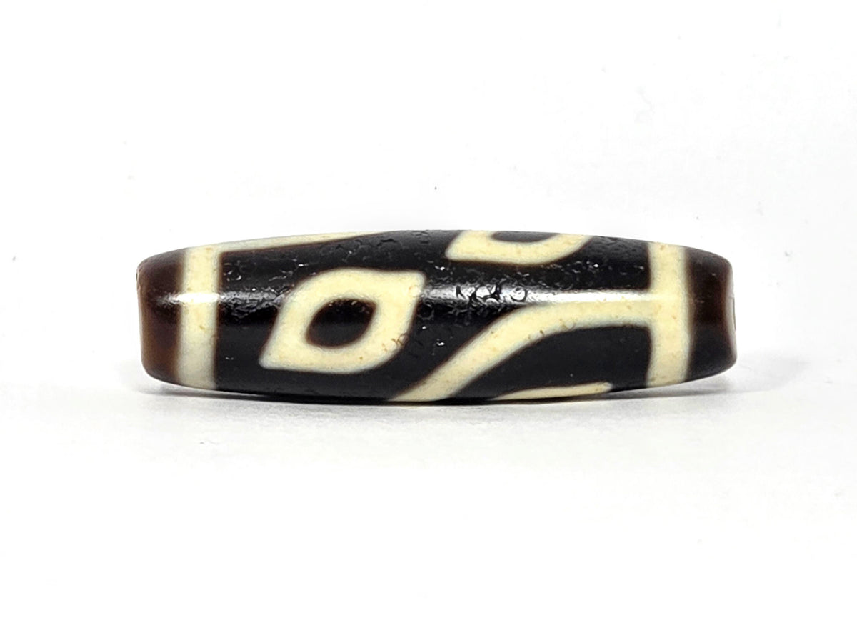 Four-eye dzi bead, dark brown and black agate, cream white eye motifs, wave pattern, aged patina, 40mm barrel shape