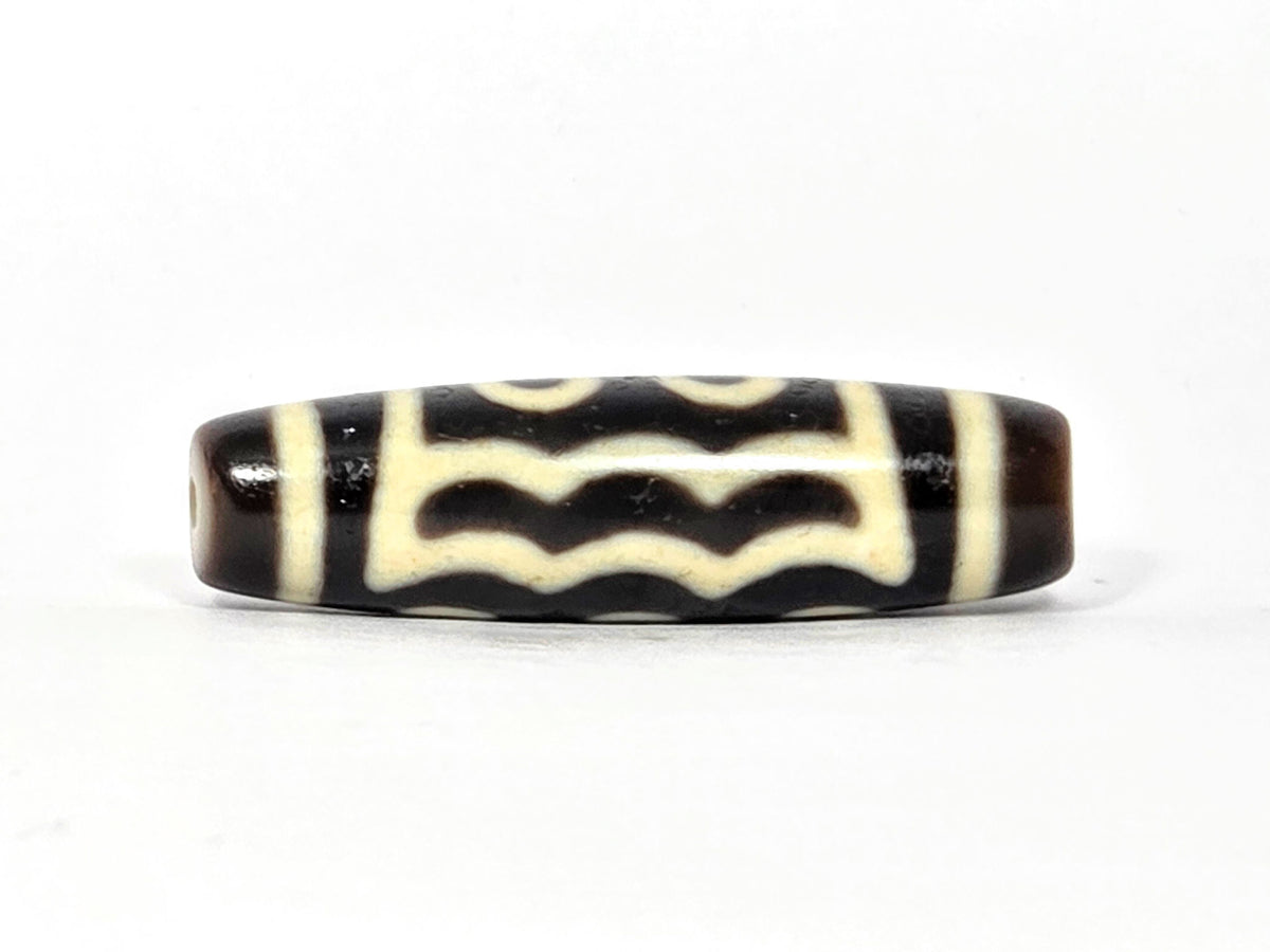 Five-eye dzi bead, dark brown agate, white wave motif, visible drill hole, glossy patina, 40.5×11.4mm
