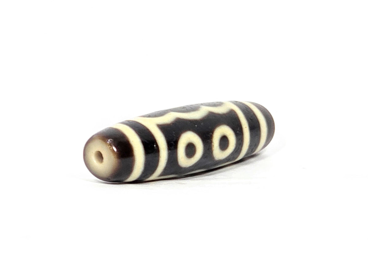 Five-eye dzi bead, dark brown agate, cream white eye motifs, wave pattern, visible drill hole, smooth patina, 40.5mm barrel shape