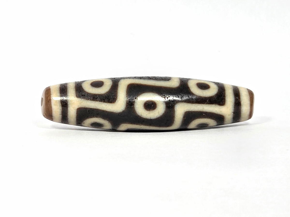 Nine-eye dzi bead with black and cream agate stripes, ancient Tibetan design, polished surface with visible drill holes