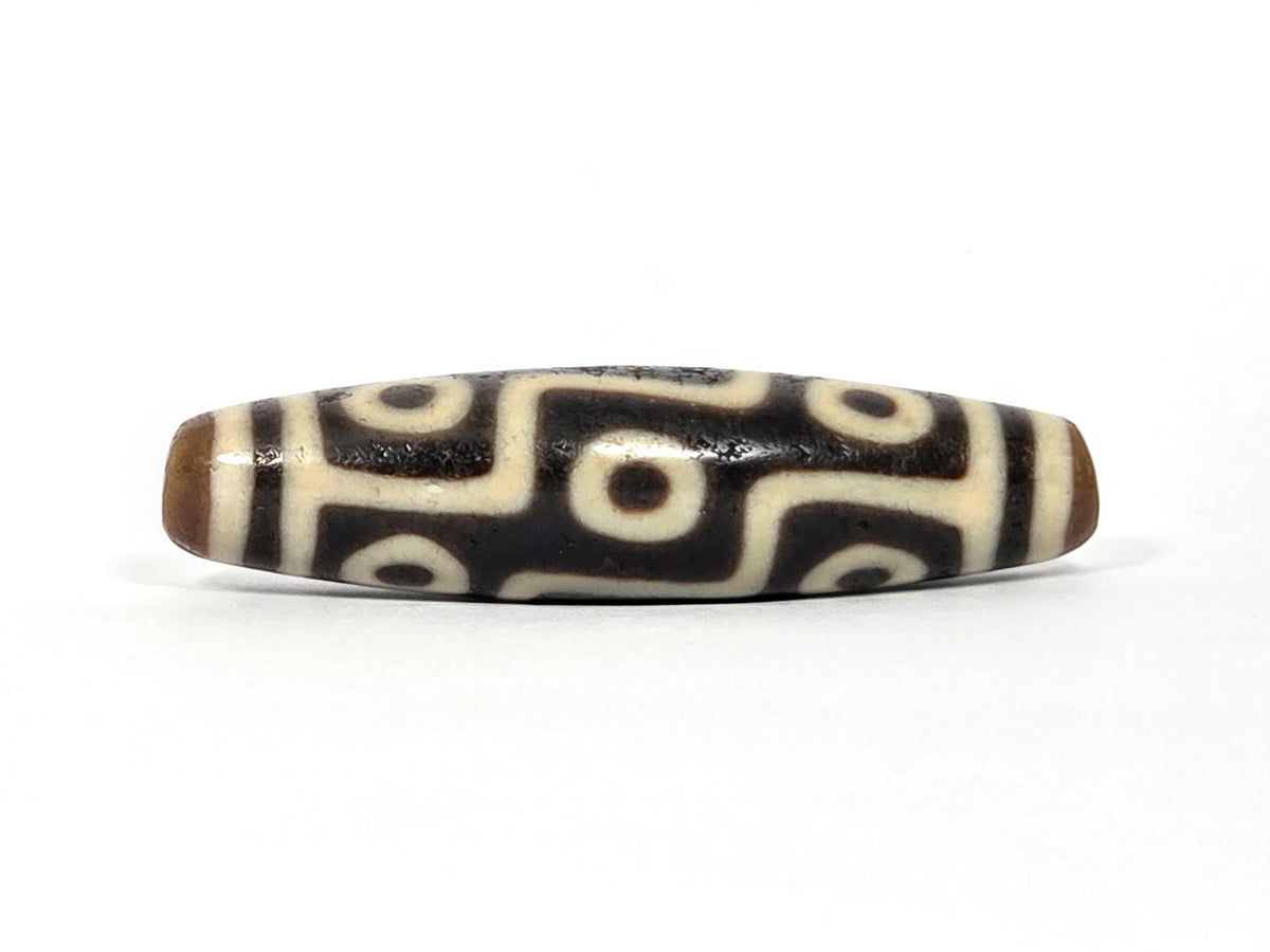 Nine-eye Tibetan dzi bead with cream and black agate pattern, polished surface, side view
