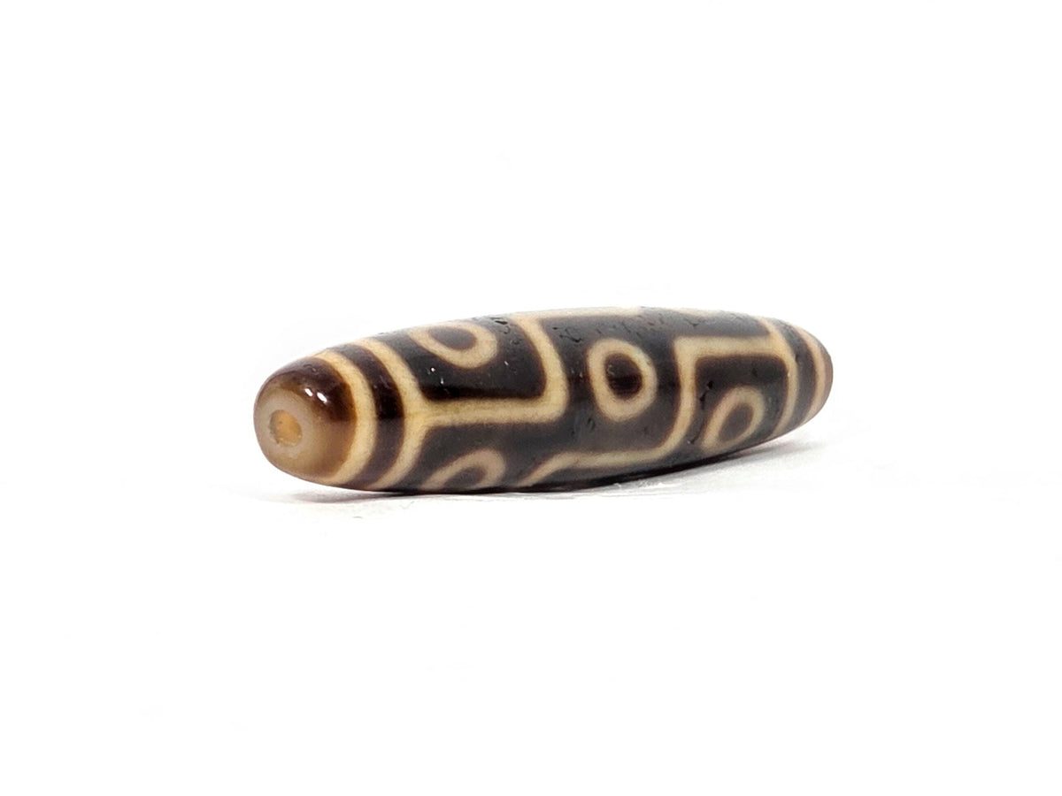 Antique Tibetan nine-eye dzi bead with brown agate and cream striped pattern, drilled hole visible