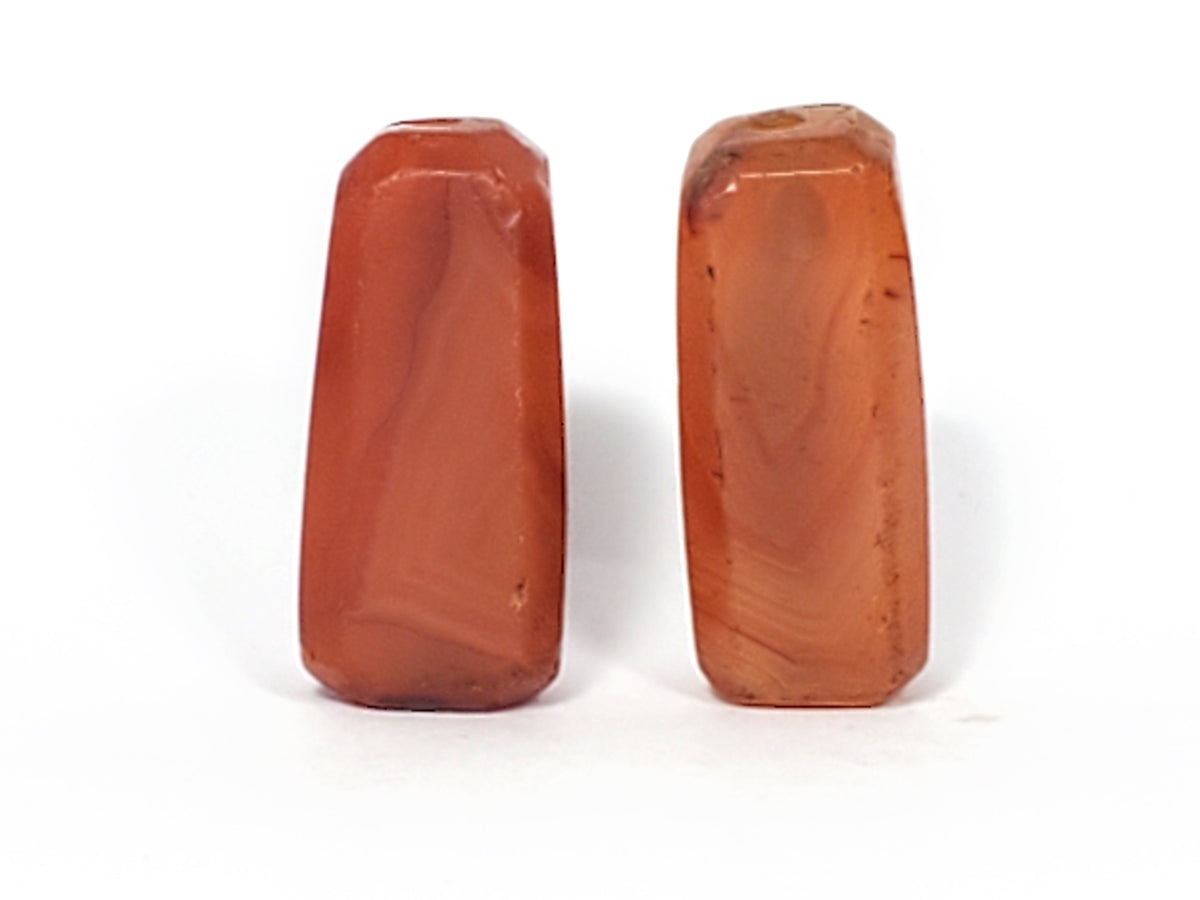 Ancient faceted carnelian beads pair, reddish-orange stone with polished surface and visible drill holes